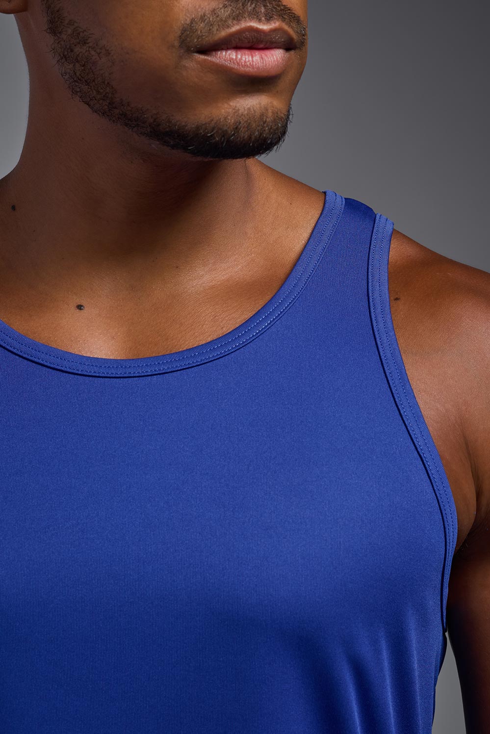 A male model wearing the men's DriMax Endurance Tank in the color royal blue, made out of 100% polyester, showing the relaxed fit from a close-up collar view. #royal