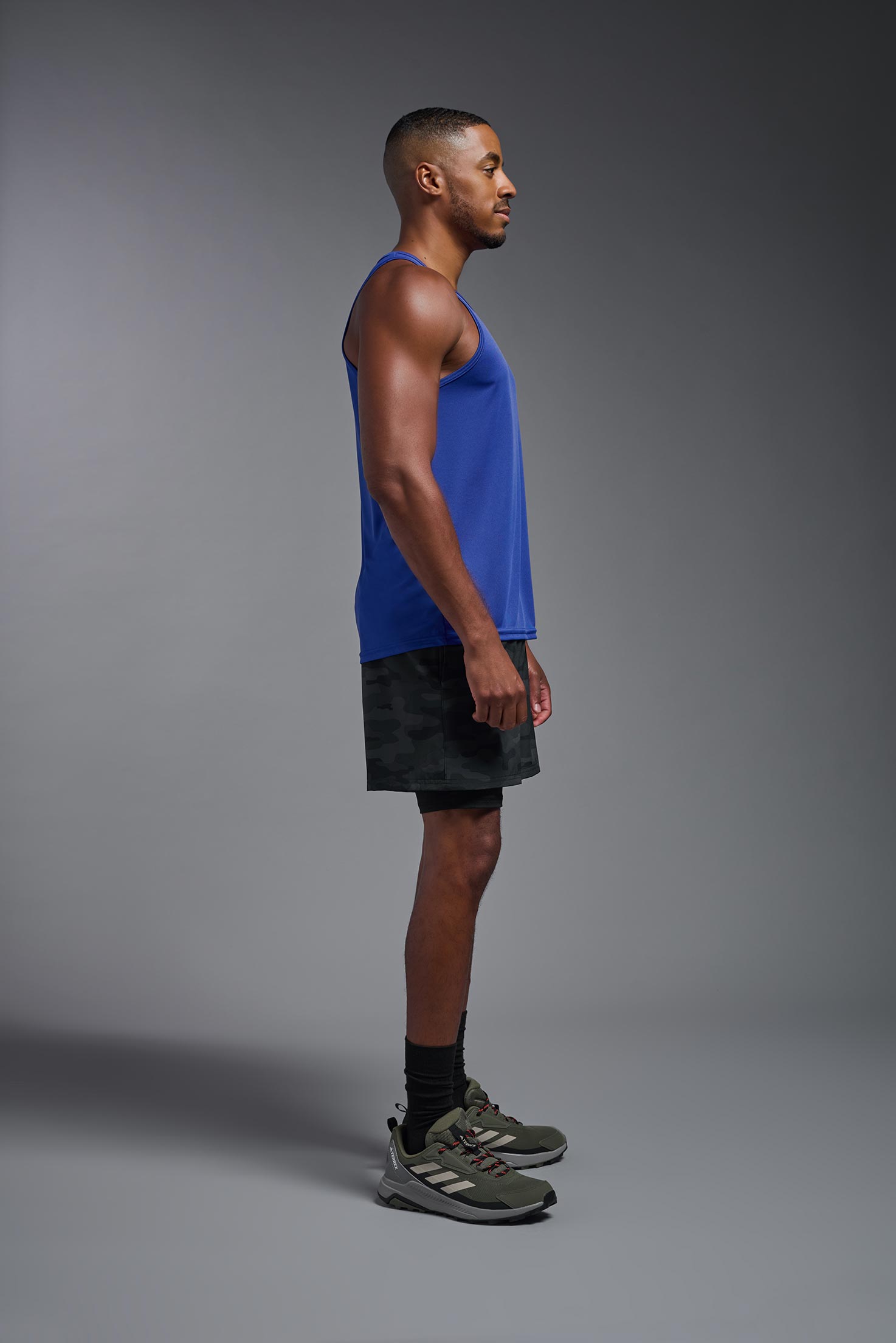 A male model wearing the men's DriMax Endurance Tank in the color royal blue, made out of 100% polyester, showing the relaxed fit from a side view. #royal
