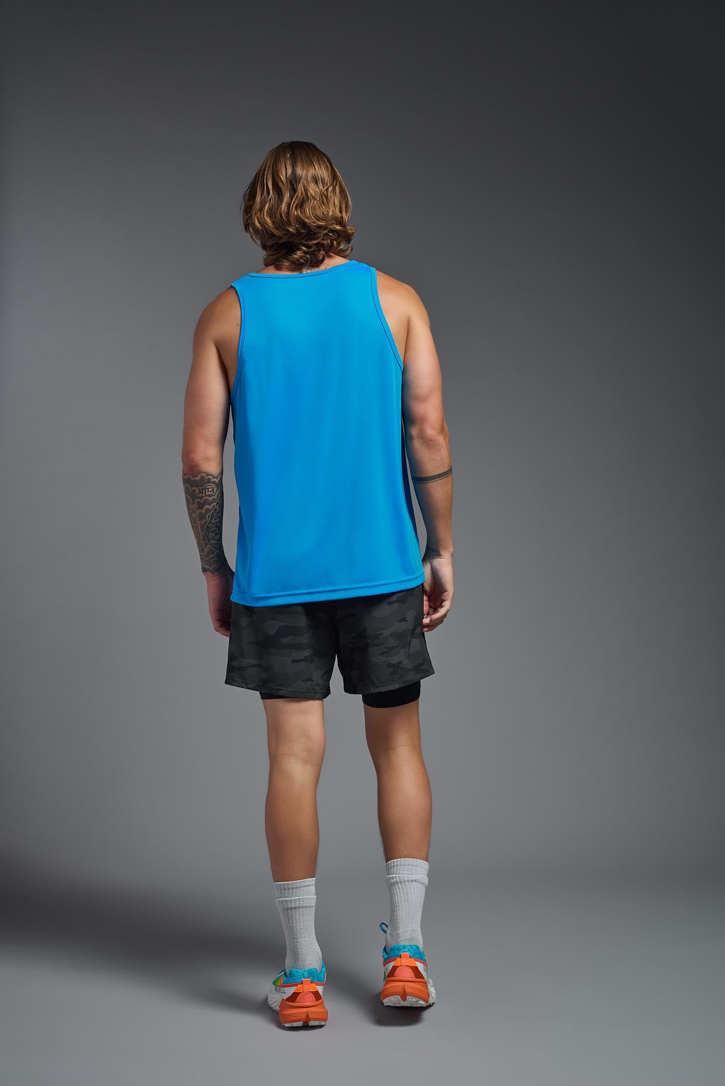 A male model wearing the men's DriMax Endurance Tank in the color safety blue, made out of 100% polyester, showing the relaxed fit from a back view. This tank is quick-drying and moisture-wicking and made in the USA #safety-blue