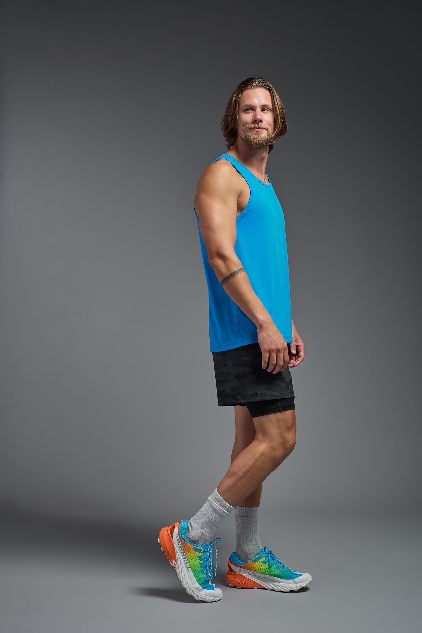 A male model wearing the men's DriMax Endurance Tank in the color safety blue, made out of 100% polyester, showing the relaxed fit from a side view. This tank is quick-drying and moisture-wicking and made in the USA #safety-blue