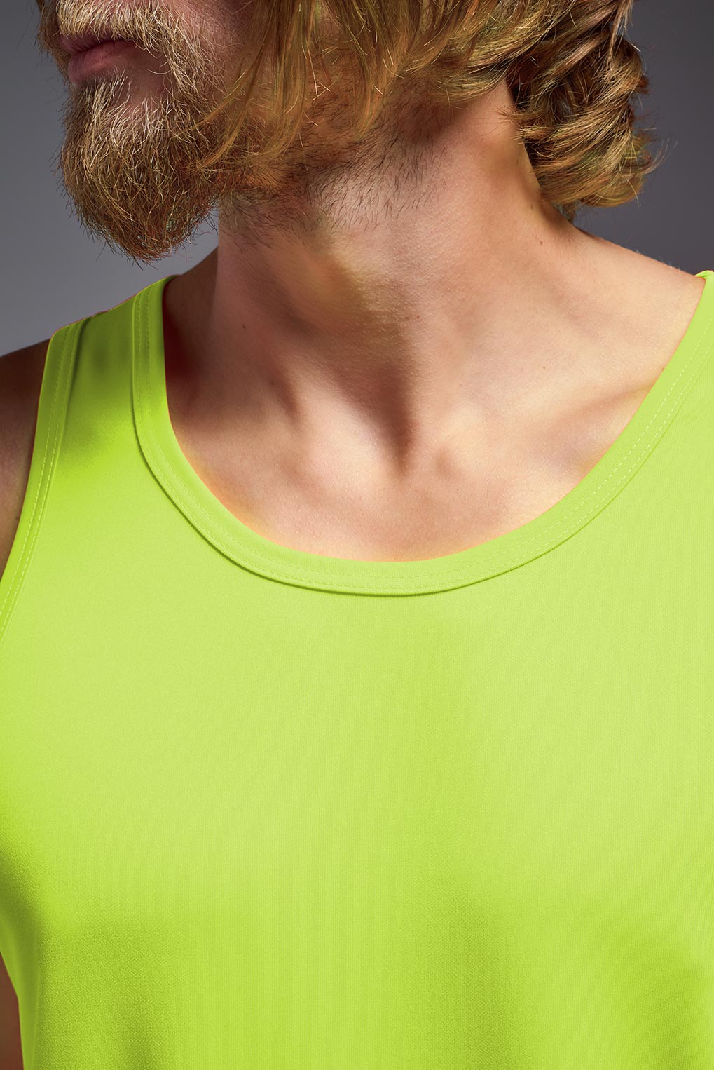 A male model wearing the men's DriMax Endurance Tank in the color safety yellow, made out of 100% polyester, showing the relaxed fit from a front closeup collar view. This tank is quick-drying and moisture-wicking and made in the USA #safety-yellow