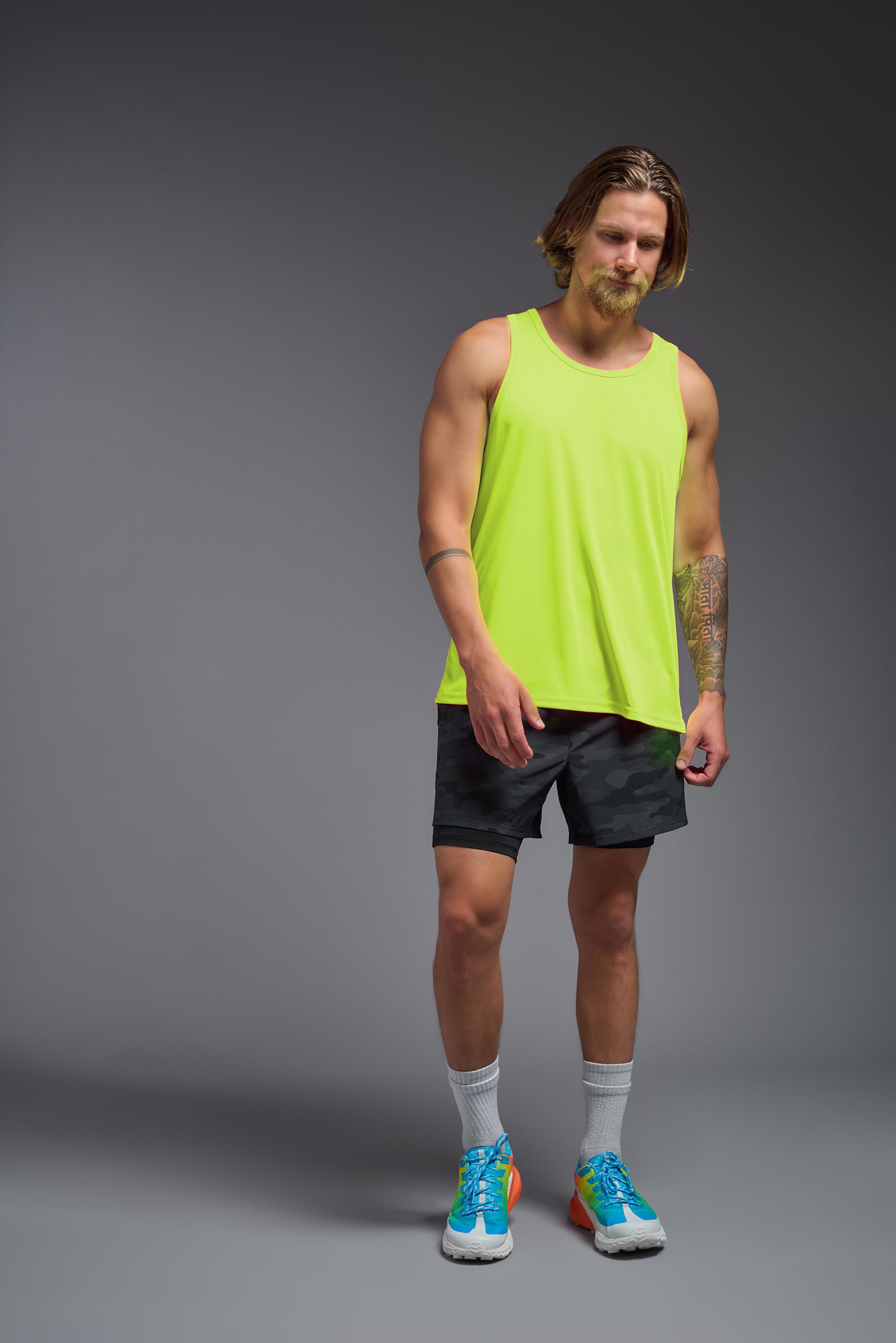 A male model wearing the men's DriMax Endurance Tank in the color safety yellow, made out of 100% polyester, showing the relaxed fit from a front view. This tank is quick-drying and moisture-wicking and made in the USA #safety-yellow