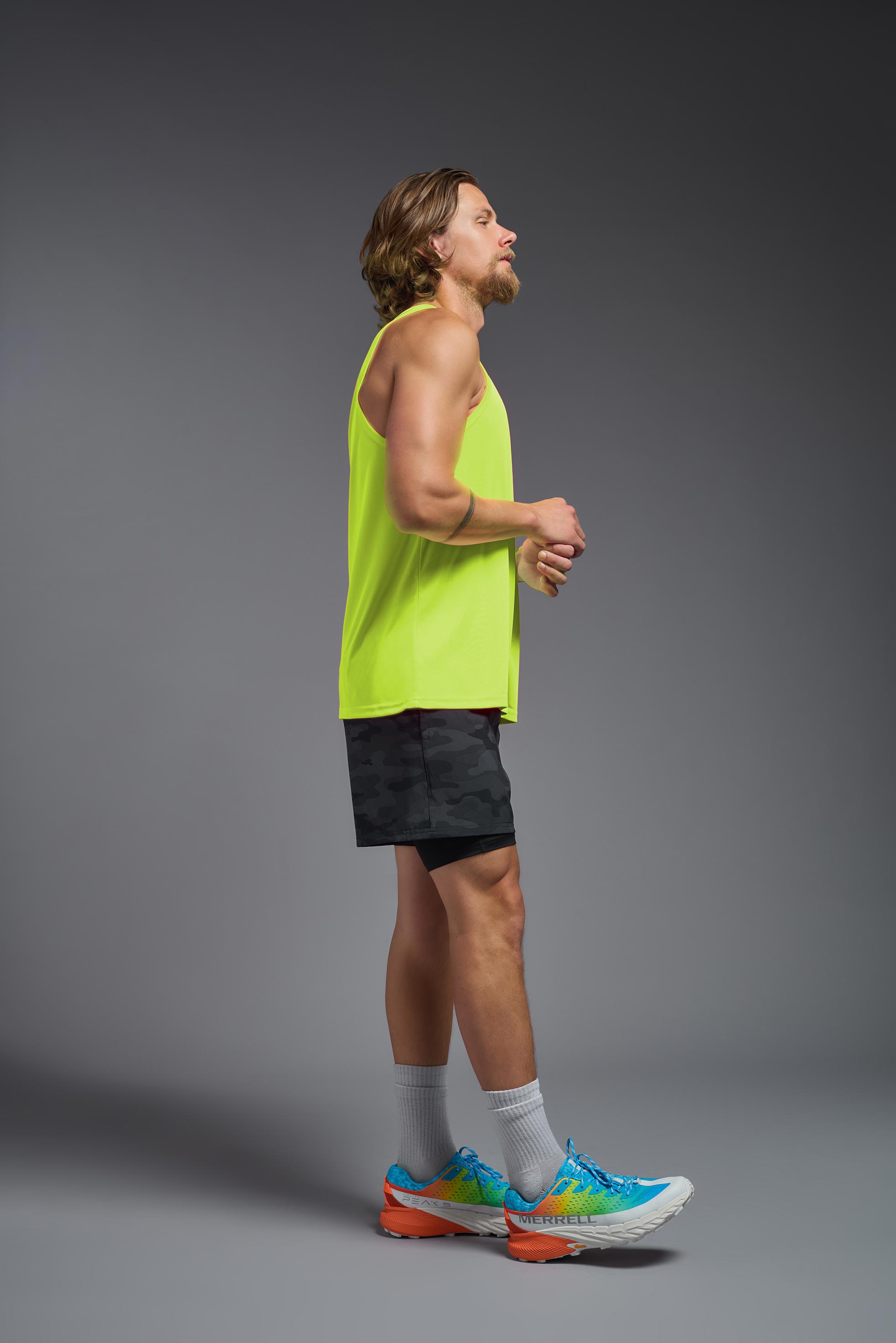 A male model wearing the men's DriMax Endurance Tank in the color safety yellow, made out of 100% polyester, showing the relaxed fit from a side
view. This tank is quick-drying and moisture-wicking and made in the USA #safety-yellow
