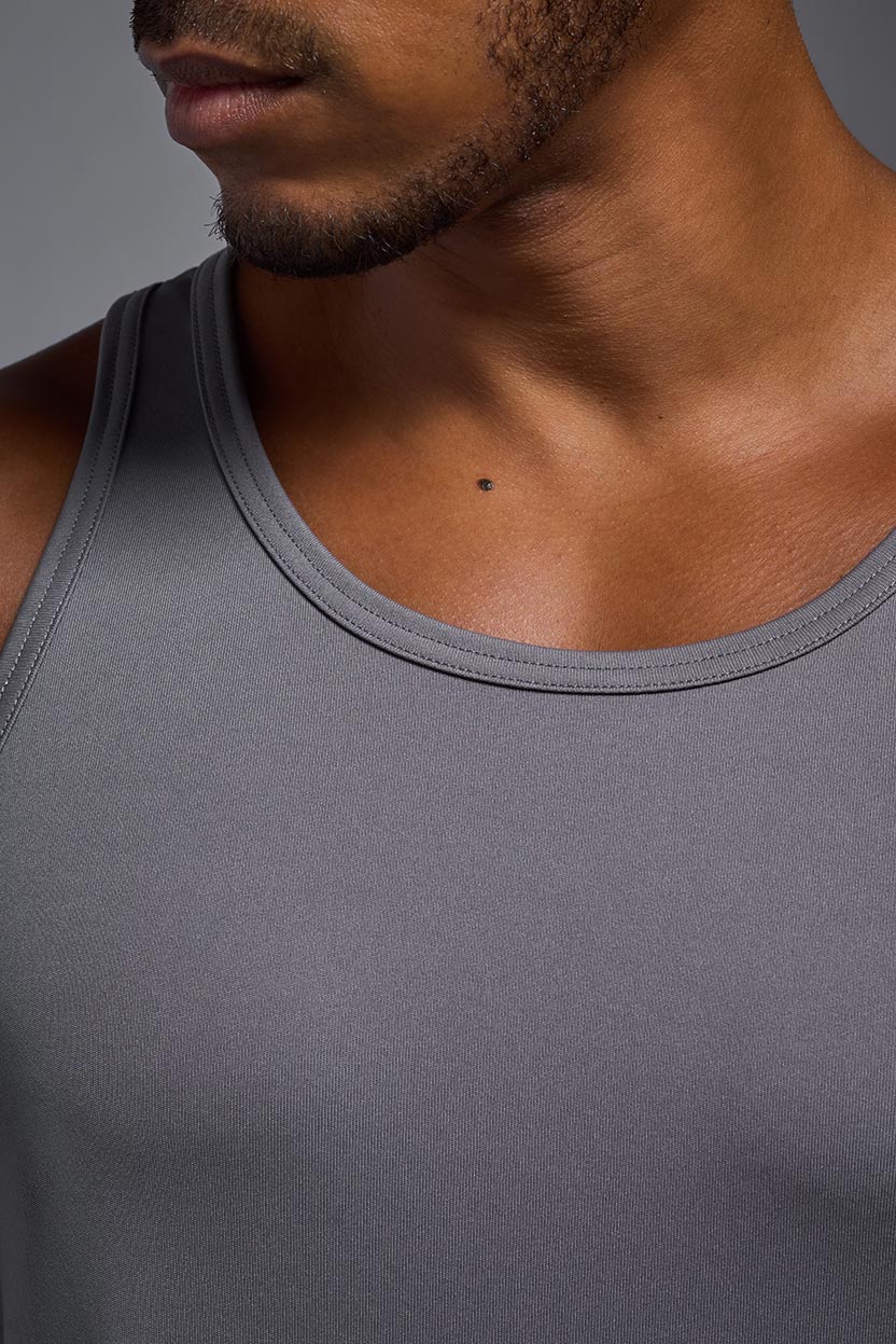 A male model wearing the men's DriMax Endurance Tank in the color steel gray, made out of 100% polyester, showing the relaxed fit from a collar close-up view. #steel