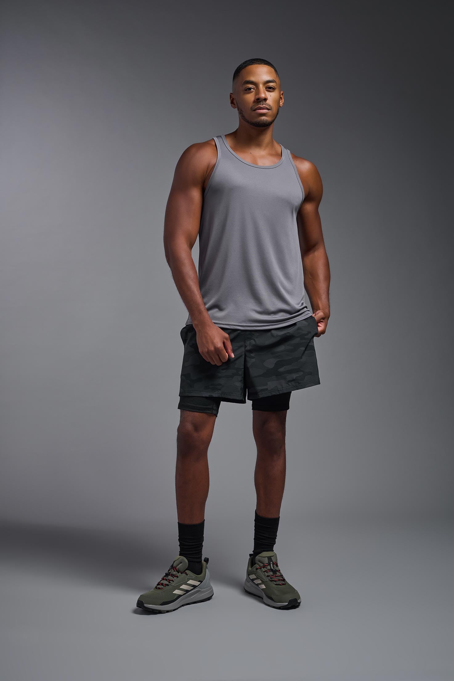 A male model wearing the men's DriMax Endurance Tank in the color steel gray, made out of 100% polyester, showing the relaxed fit from a front view. #steel