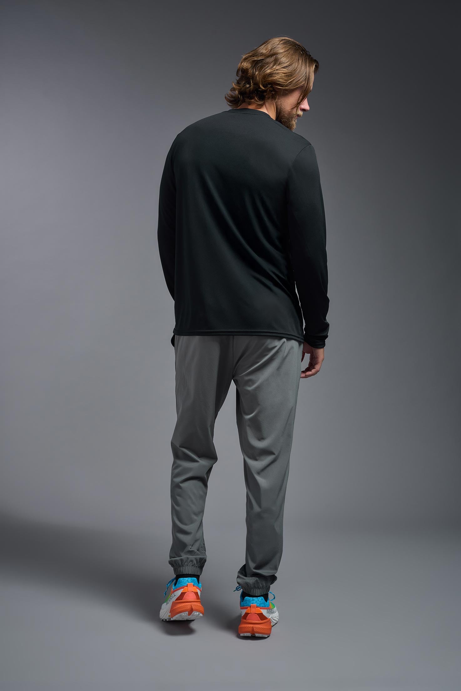 A male model wearing the men's DriMax Long Sleeve Expert Tee in black, made out of 100% polyester, showing the relaxed fit from a back view. #black