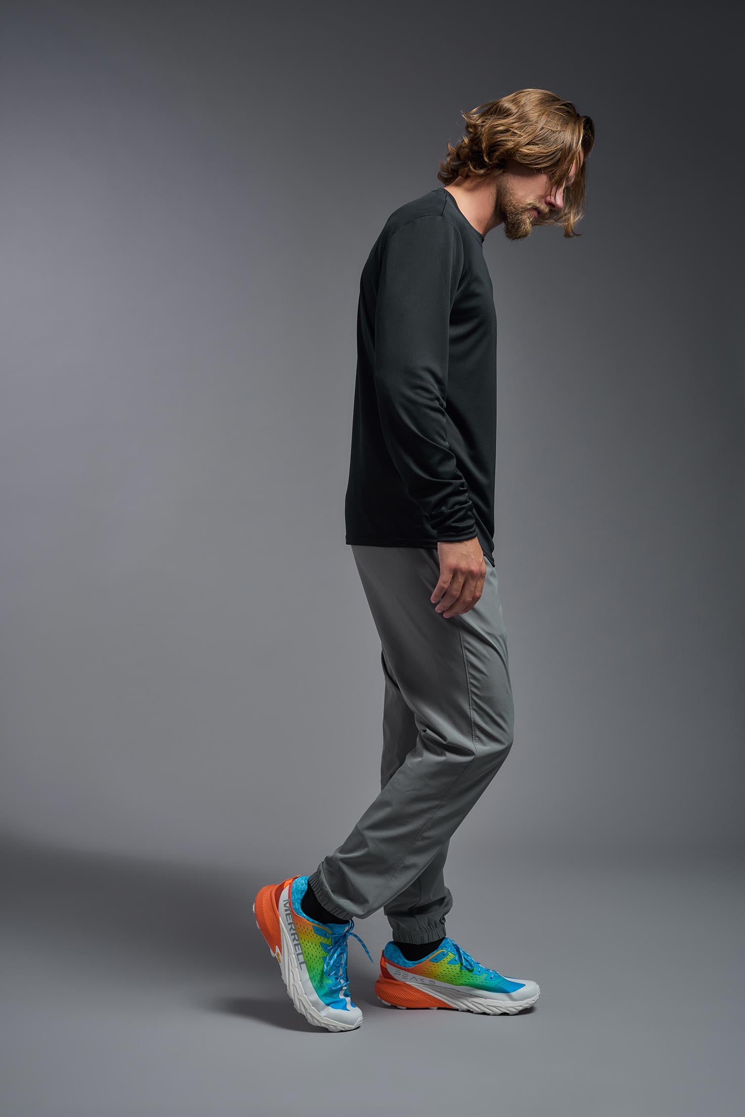 A male model wearing the men's DriMax Long Sleeve Expert Tee in black, made out of 100% polyester, showing the relaxed fit from a side view. #black