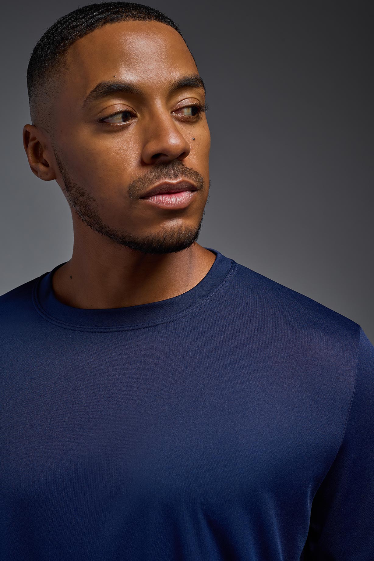 A male model wearing the men's DriMax Long Sleeve Expert Tee in the color navy blue, made out of 100% polyester, showing the relaxed fit from a collar detail view. #navy