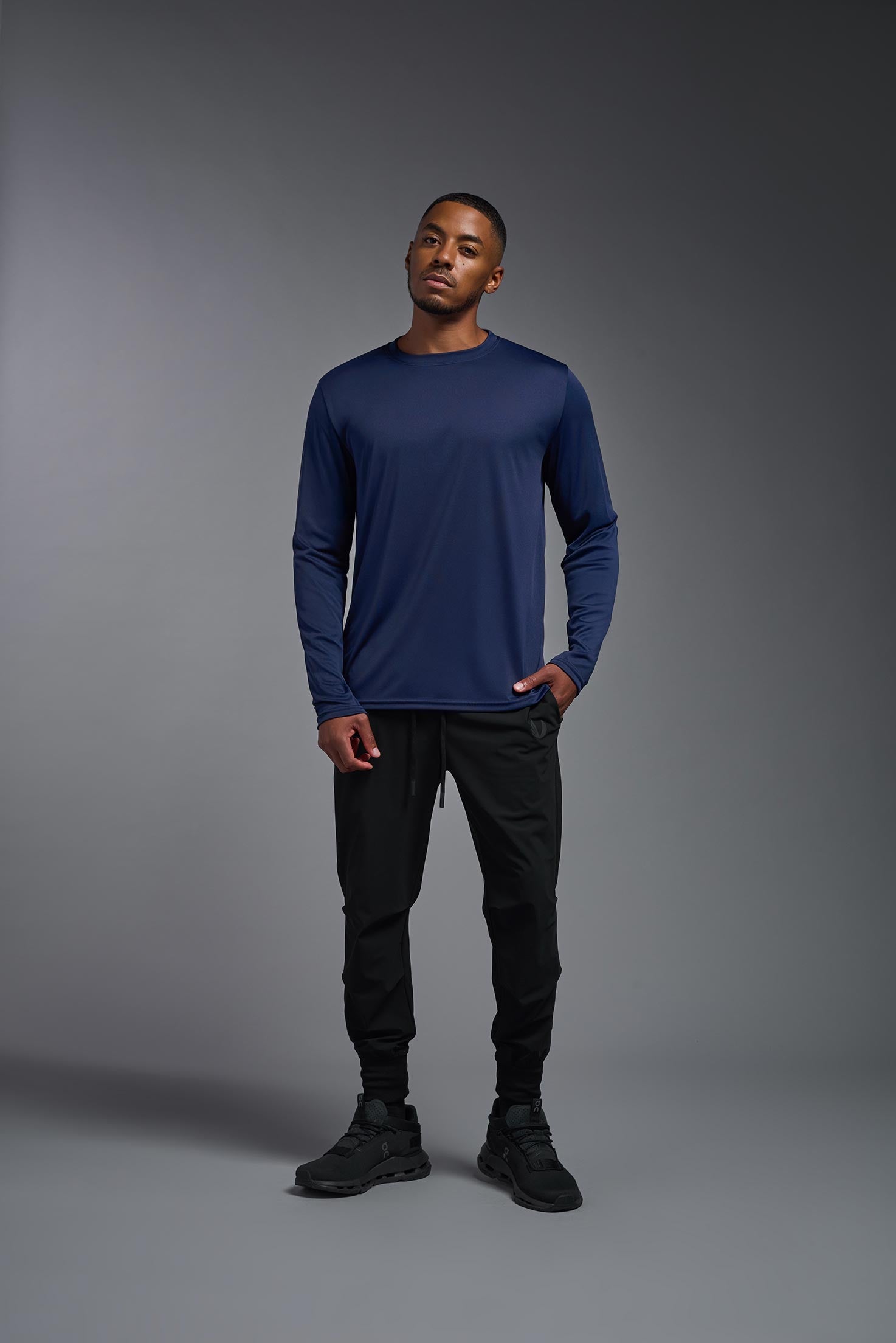A male model wearing the men's DriMax Long Sleeve Expert Tee in the color  navy blue, made out of 100% polyester, showing the relaxed fit from a front view. #navy