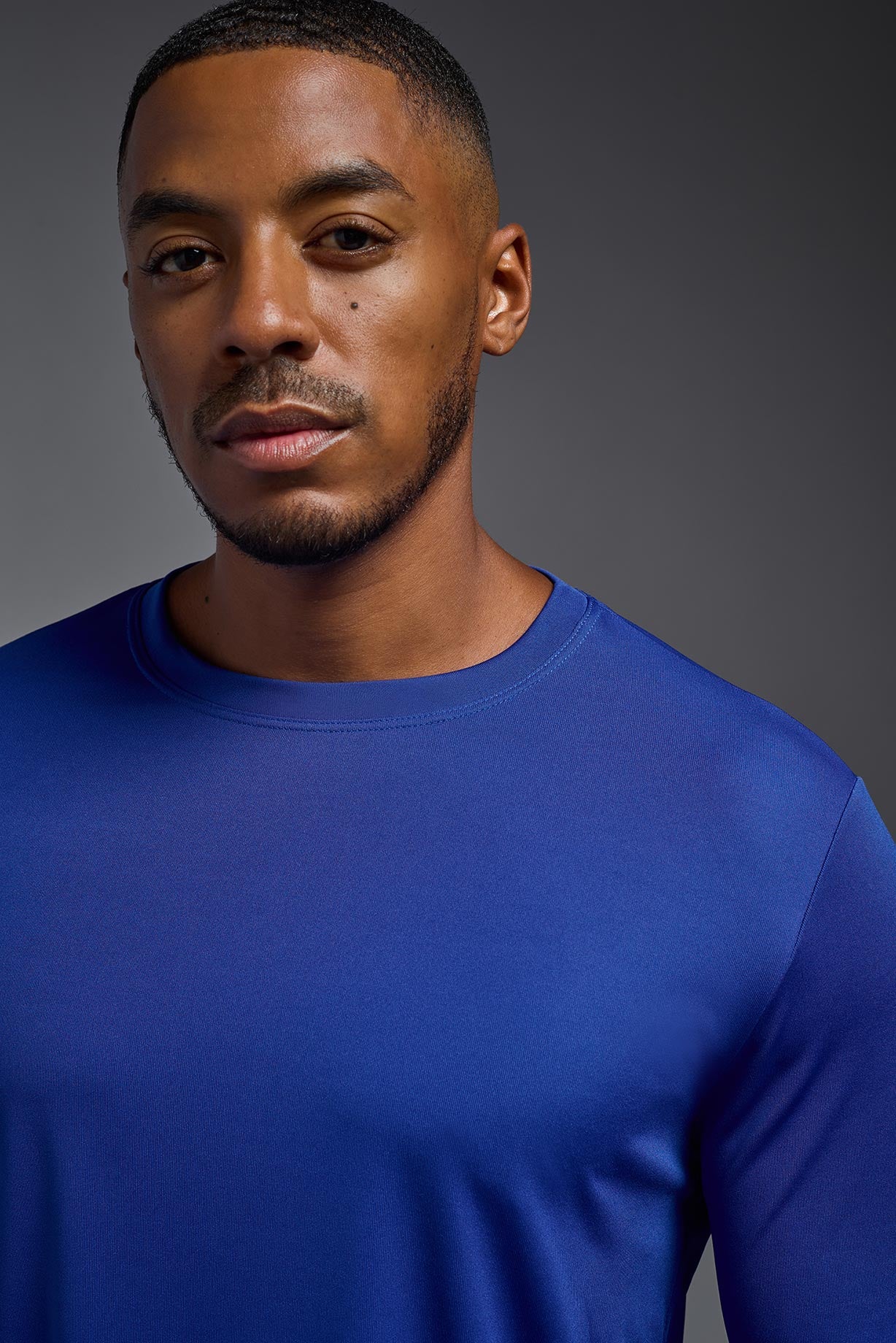 A male model wearing the men's DriMax Long Sleeve Expert Tee in the color royal blue, made out of 100% polyester, showing the relaxed fit from a collar view. #royal