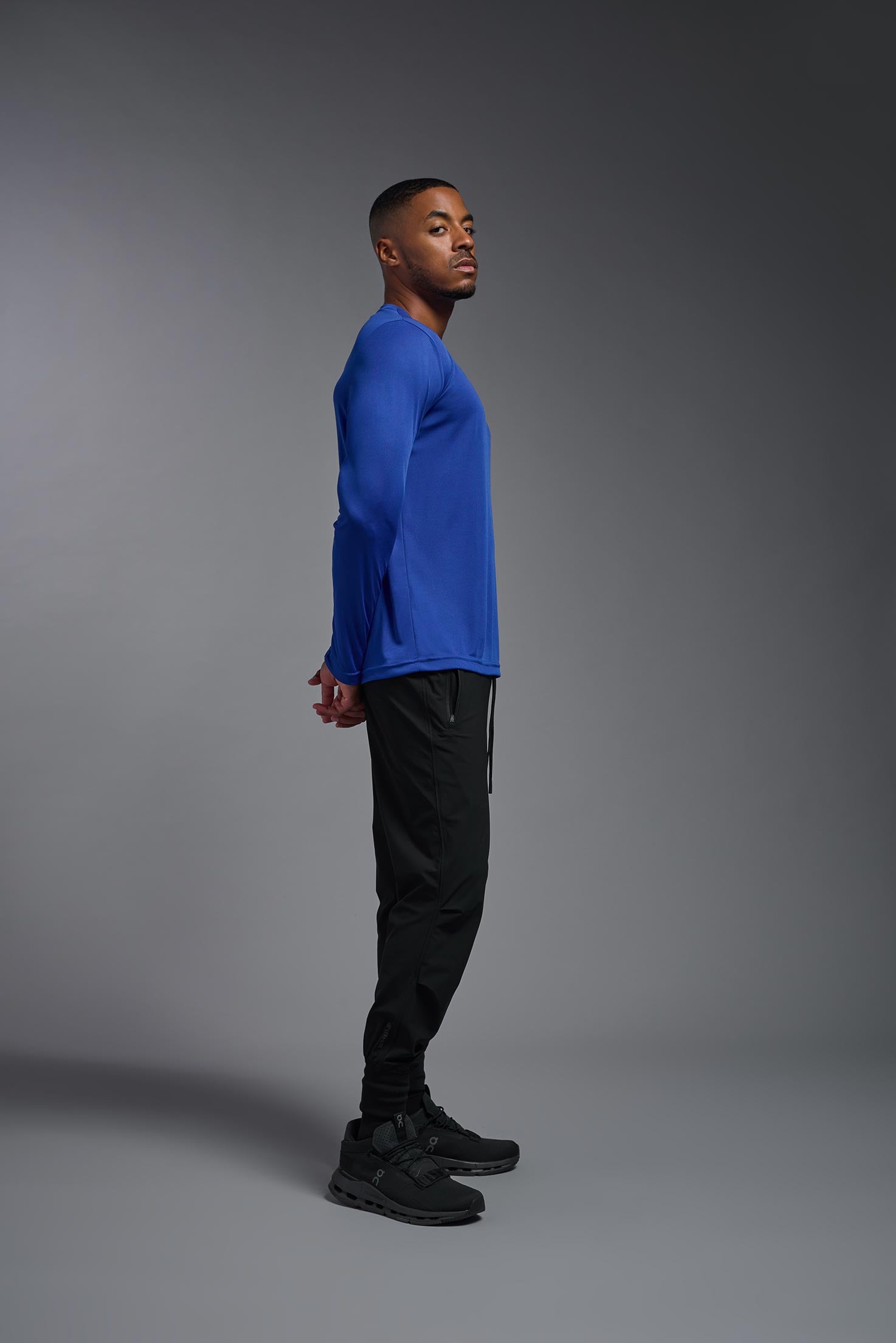A male model wearing the men's DriMax Long Sleeve Expert Tee in the color royal blue, made out of 100% polyester, showing the relaxed fit from a side view. #royal