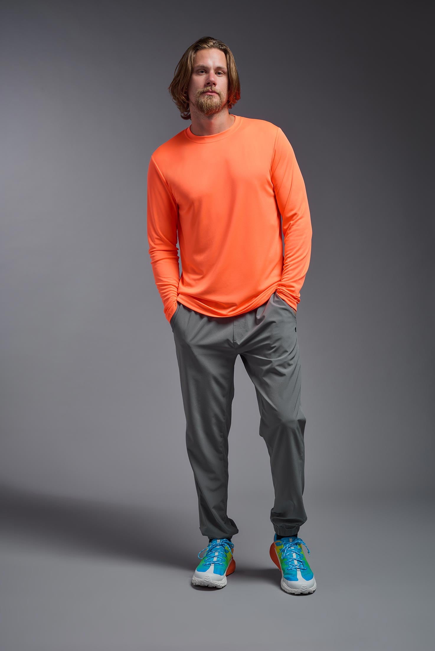 A male model wearing the men's DriMax Long Sleeve Expert Tee in the color safety orange, made out of 100% polyester, showing the relaxed fit from a front view. #safety-orange
