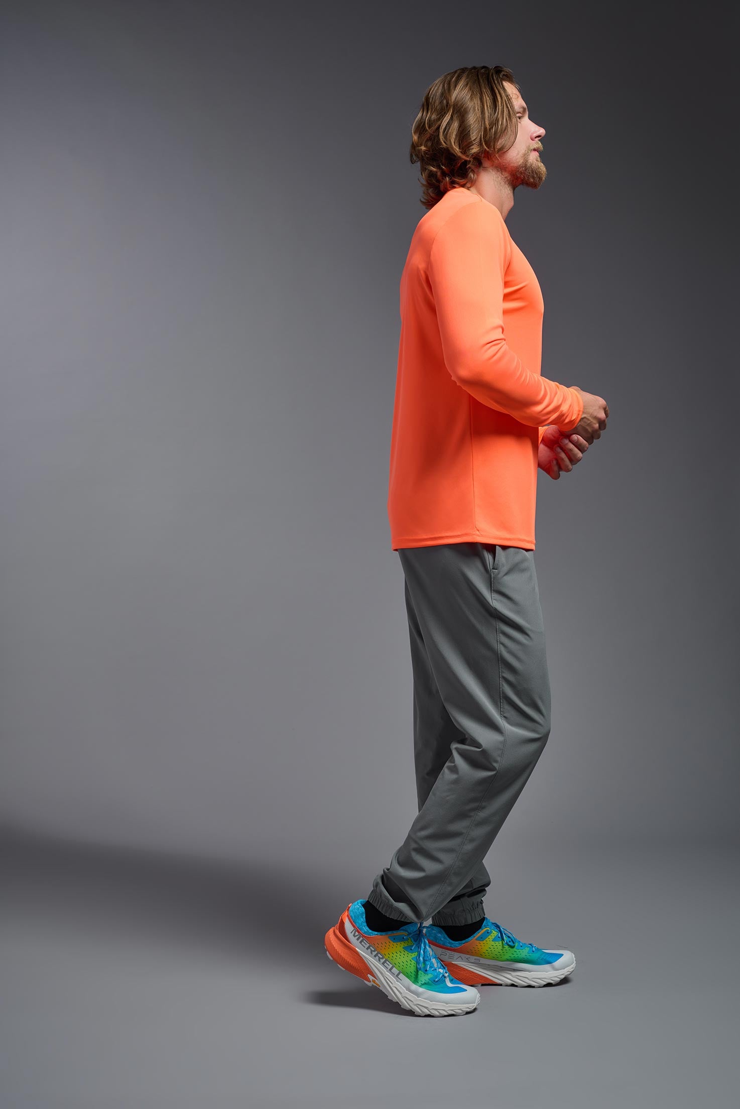 A male model wearing the men's DriMax Long Sleeve Expert Tee in the color safety orange, made out of 100% polyester, showing the relaxed fit from a side view. #safety-orange
