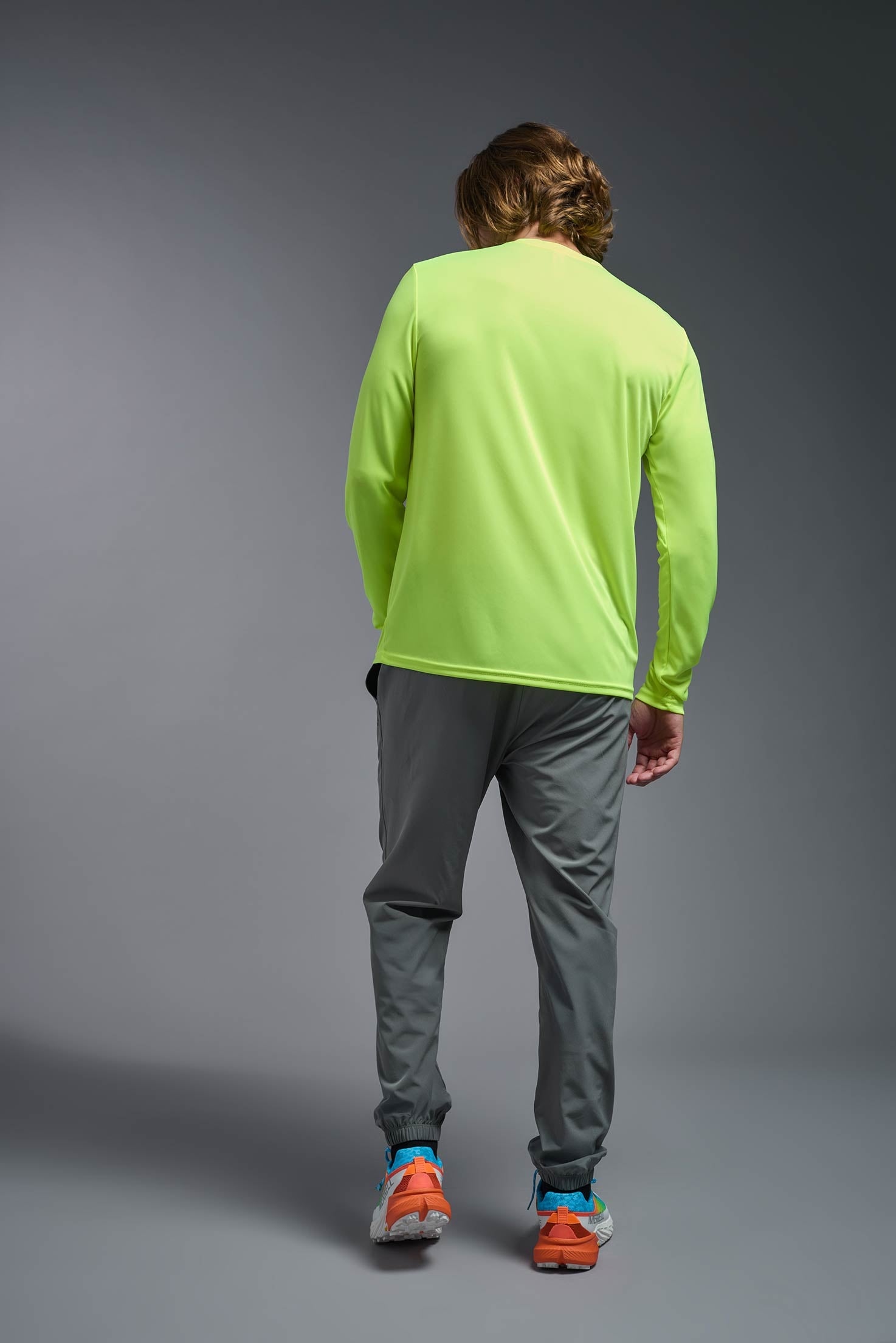 A male model wearing the men's DriMax Long Sleeve Expert Tee in safety yellow, made out of 100% polyester, showing the relaxed fit from a back view. #safety-yellow