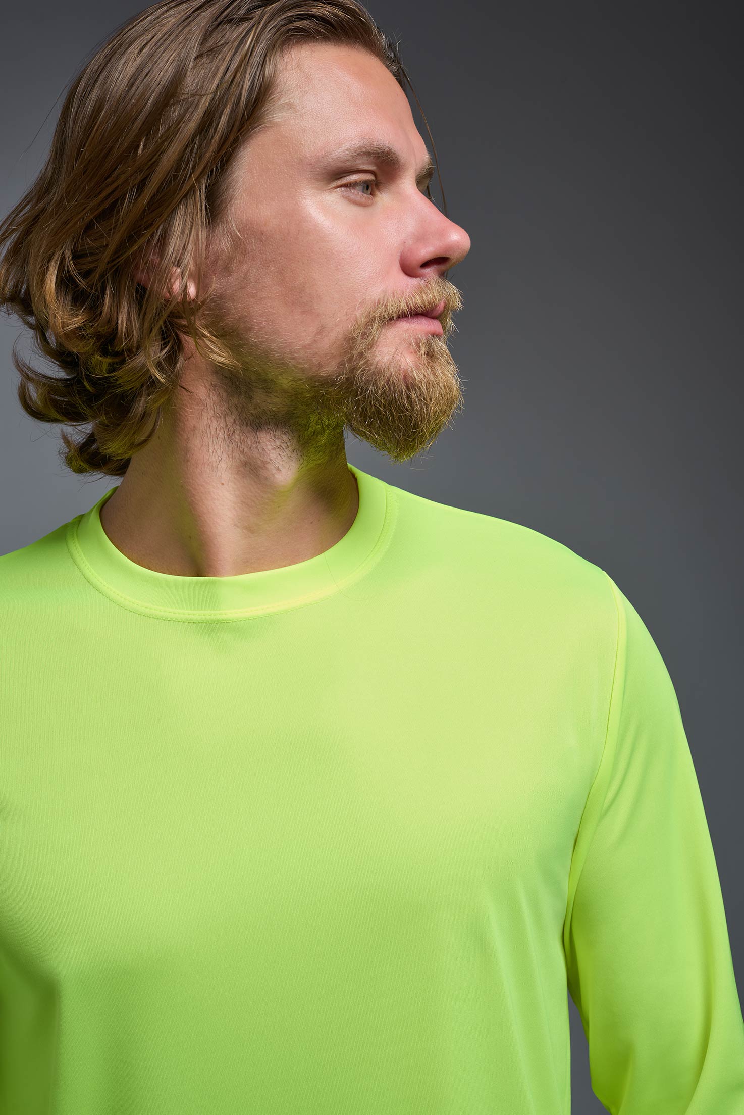A male model wearing the men's DriMax Long Sleeve Expert Tee in safety yellow, made out of 100% polyester, showing the relaxed fit from a detail collar view. #safety-yellow