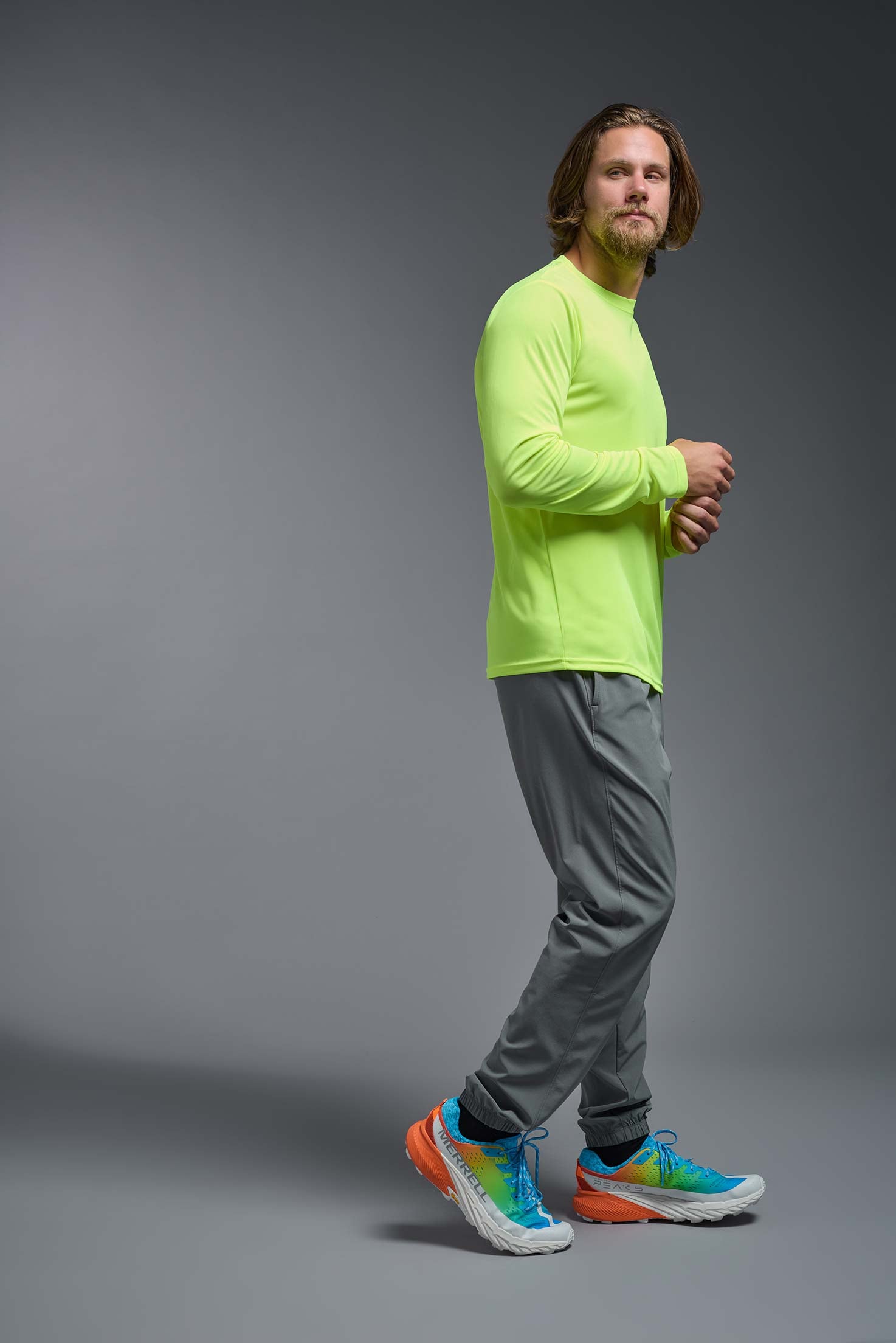 A male model wearing the men's DriMax Long Sleeve Expert Tee in safety yellow, made out of 100% polyester, showing the relaxed fit from a side view. #safety-yellow