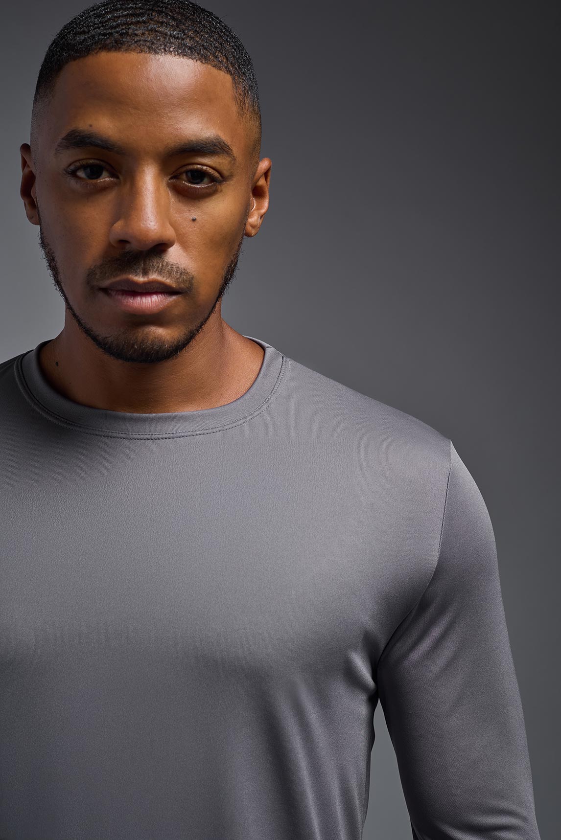 A male model wearing the men's DriMax Long Sleeve Expert Tee in steel, made out of 100% polyester, showing the relaxed fit from a detail collar view. #steel