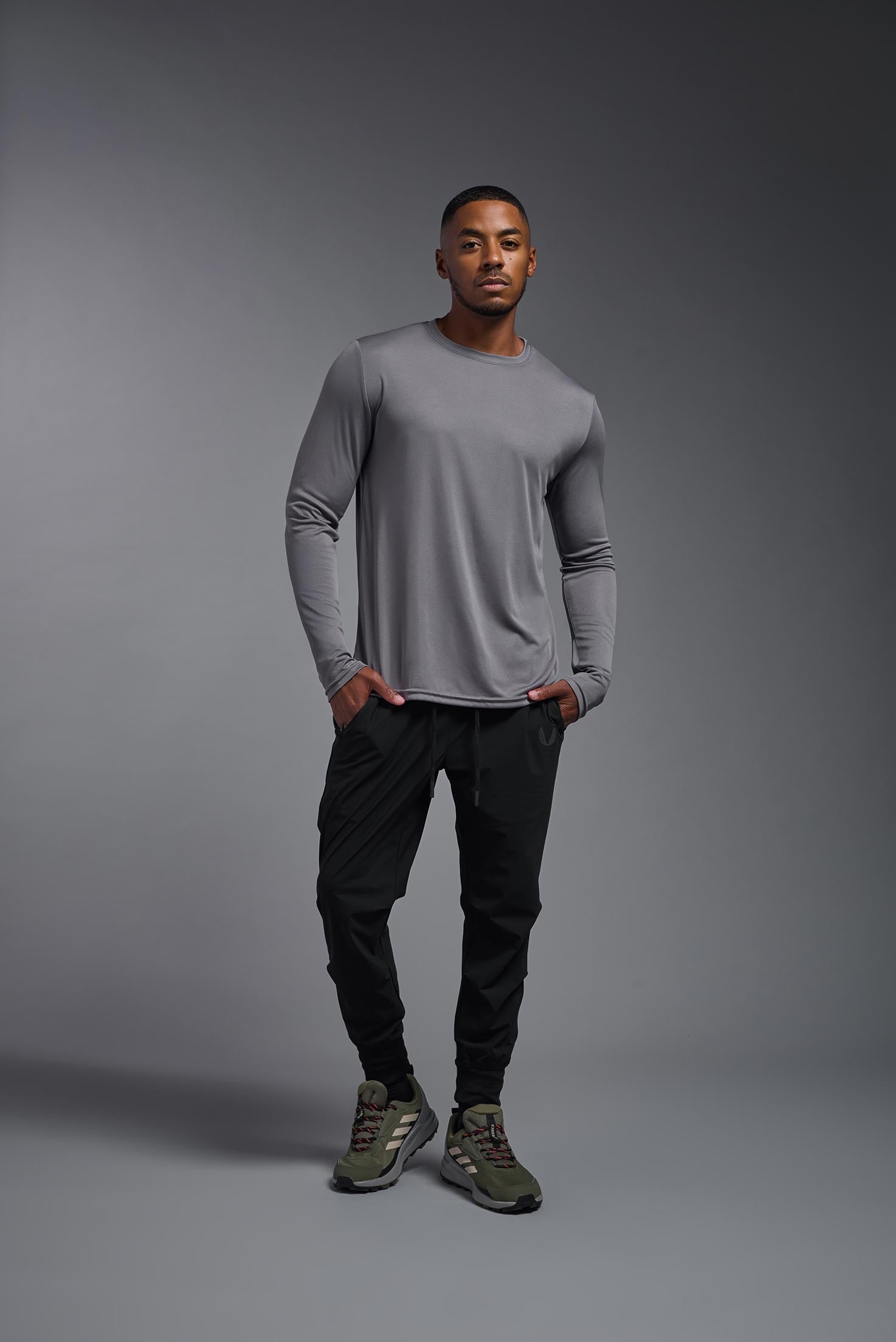 A male model wearing the men's DriMax Long Sleeve Expert Tee in steel, made out of 100% polyester, showing the relaxed fit from a front view. #steel