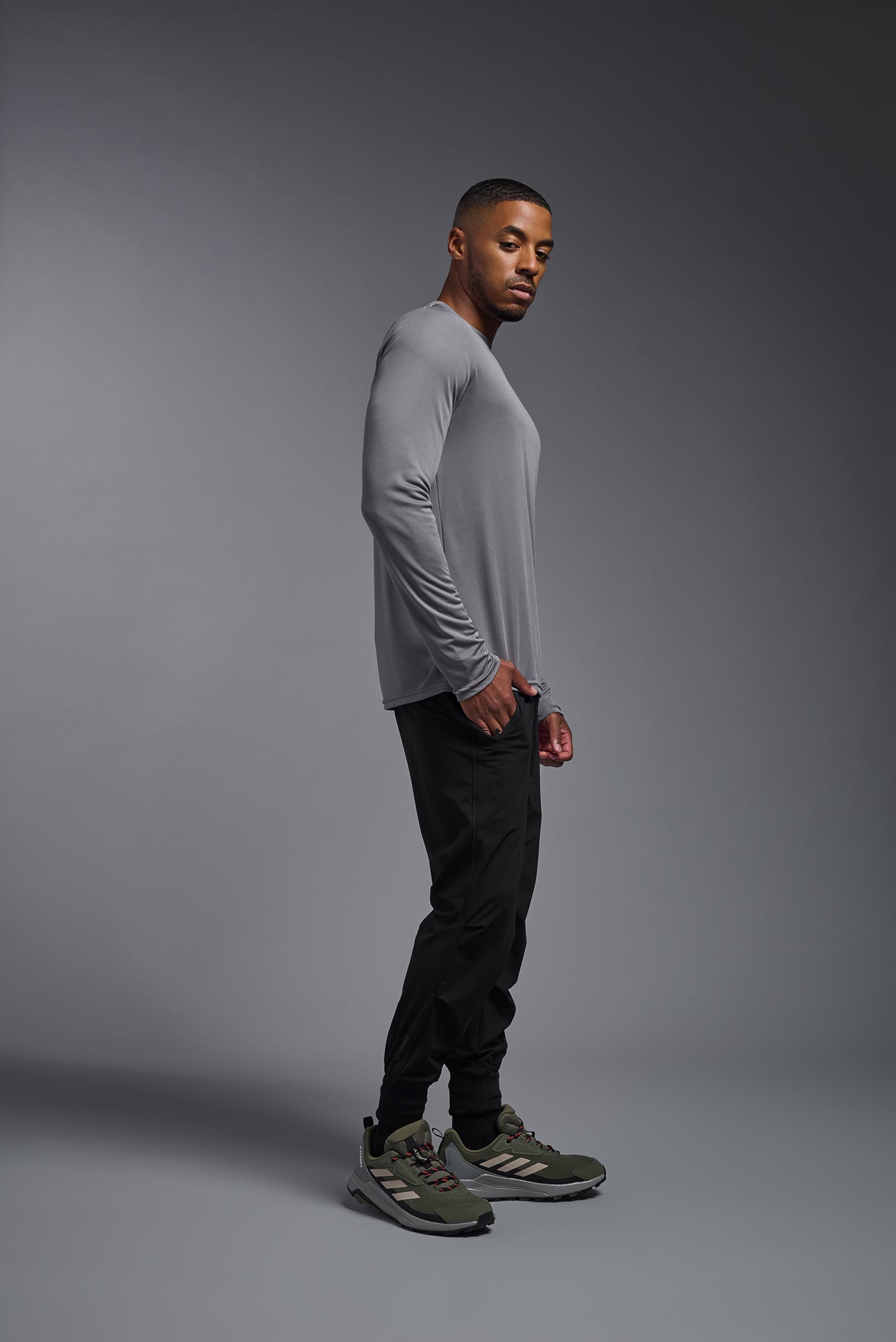 A male model wearing the men's DriMax Long Sleeve Expert Tee in the color steel, made out of 100% polyester, showing the relaxed fit from a side view. #steel