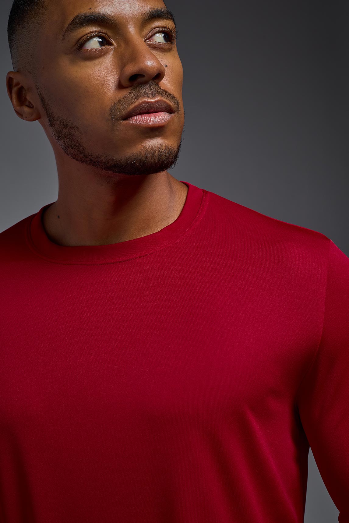 A male model wearing the men's DriMax Long Sleeve Expert Tee in red, made out of 100% polyester, showing the relaxed fit from a detail collar view. #red