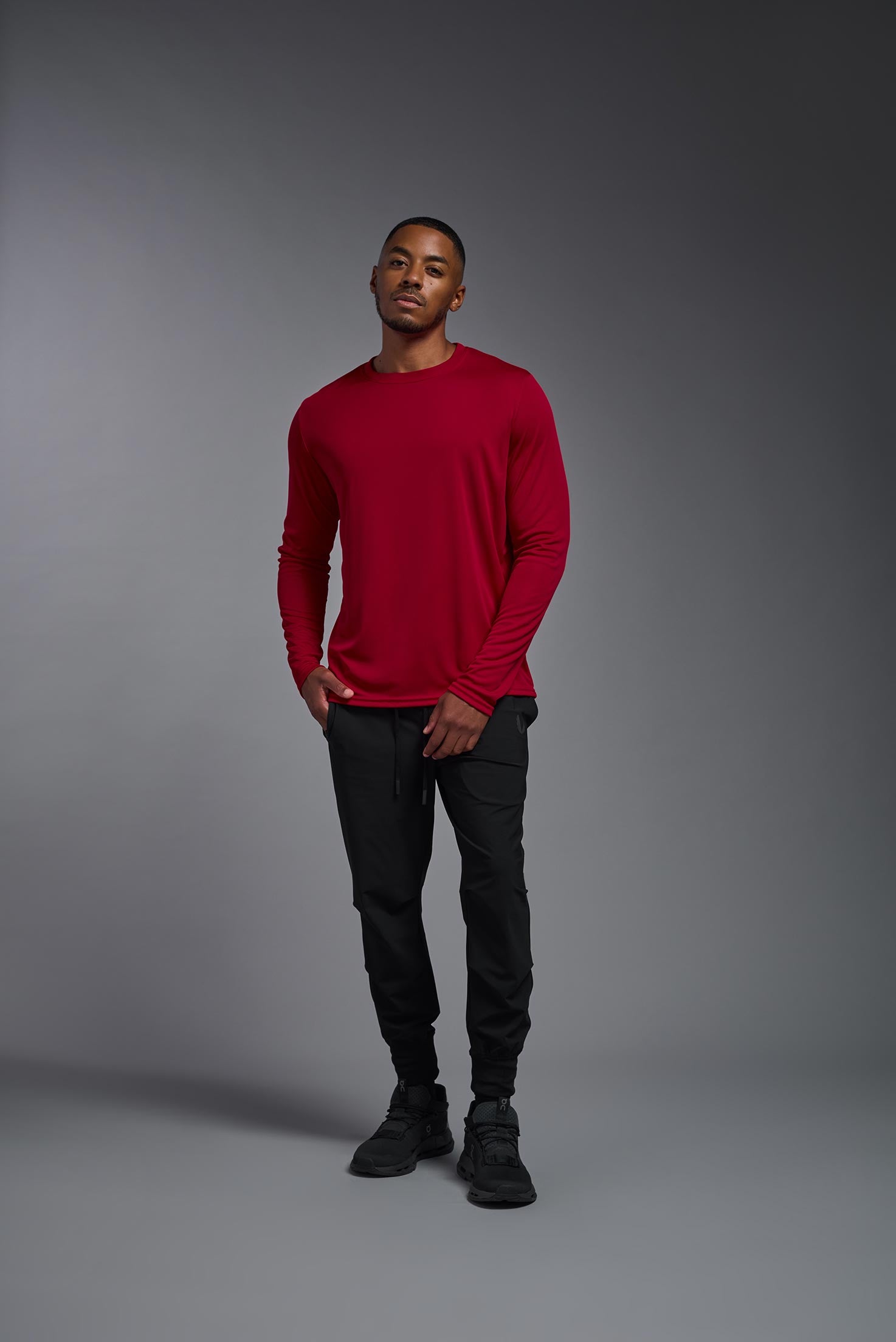 A male model wearing the men's DriMax Long Sleeve Expert Tee in red, made out of 100% polyester, showing the relaxed fit from a front view. #red