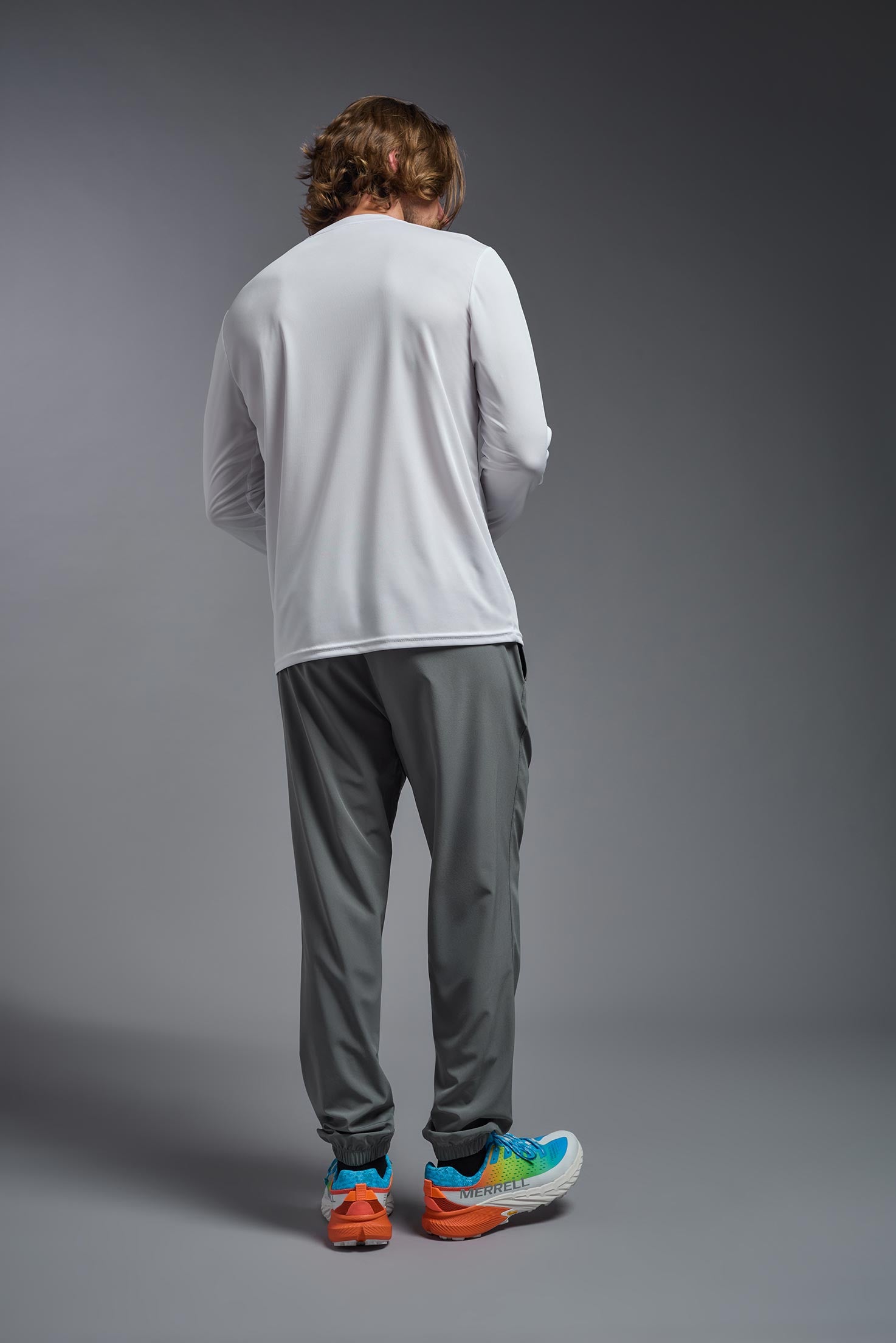 A male model wearing the men's DriMax Long Sleeve Expert Tee in the color white, made out of 100% polyester, showing the relaxed fit from a back view. #white