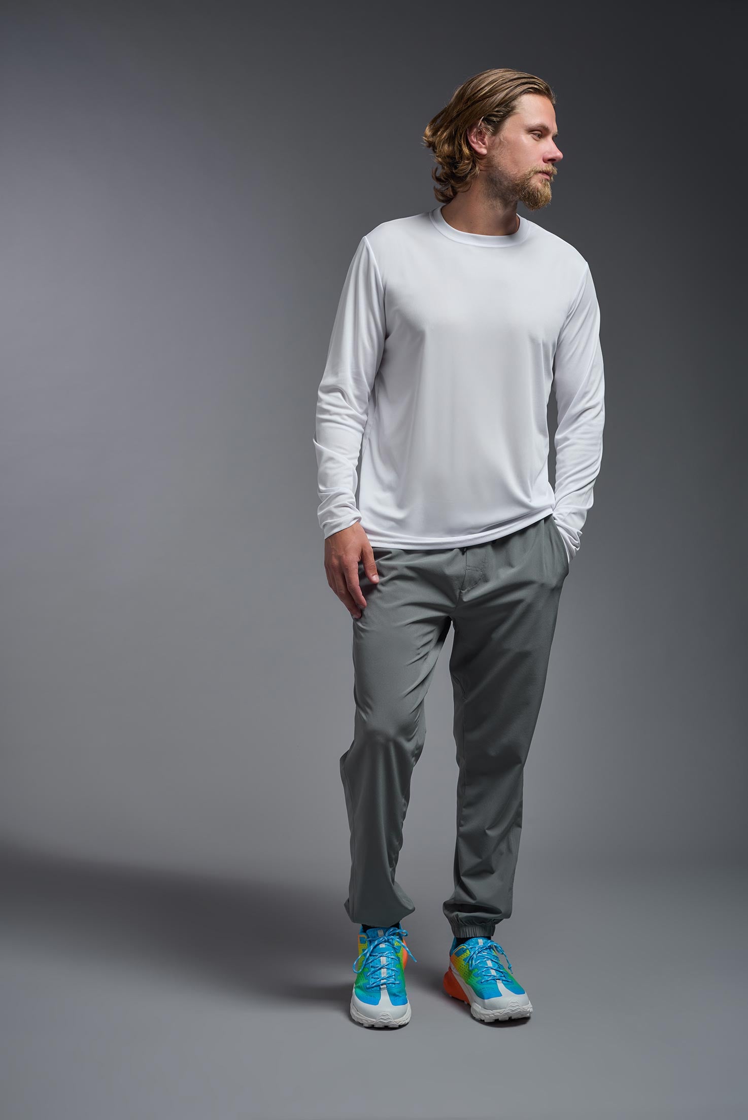 A male model wearing the men's DriMax Long Sleeve Expert Tee in the color white, made out of 100% polyester, showing the relaxed fit from a front view. #white