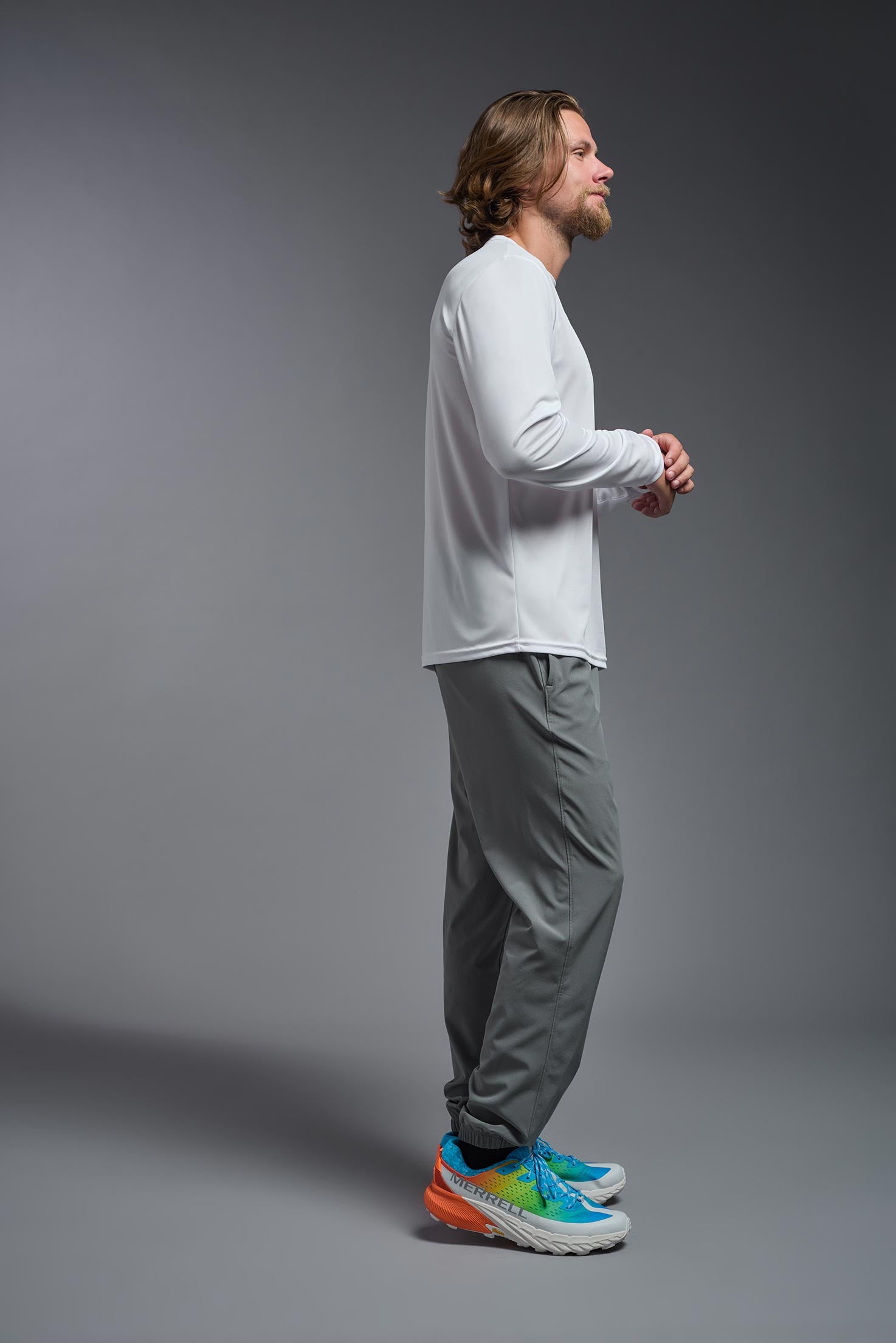 A male model wearing the men's DriMax Long Sleeve Expert Tee in the color white, made out of 100% polyester, showing the relaxed fit from a side view. #white