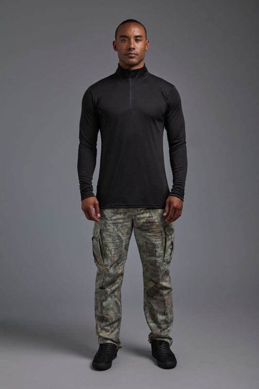 A male model wearing the men's DriMax Quarterzip Training Top in the color black, made out of 100% polyester, showing the relaxed fit from a front view. This Quarter Zip is made in the USA wicks sweat, quick dries like drifit, and controls odors. #black