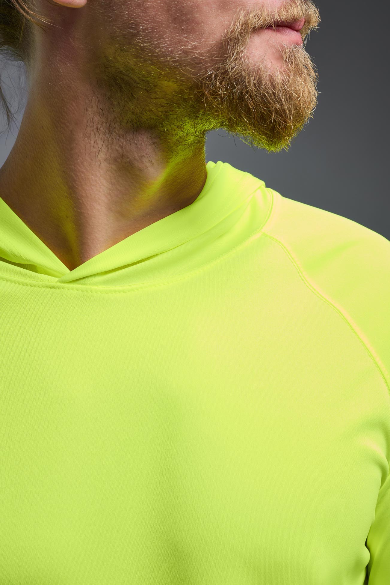 A male model wearing the men's DriMax Lightweight Hoodie in the color safety yellow, made out of 100% polyester, showing the relaxed fit from a close-up collar view. #safety-yellow
