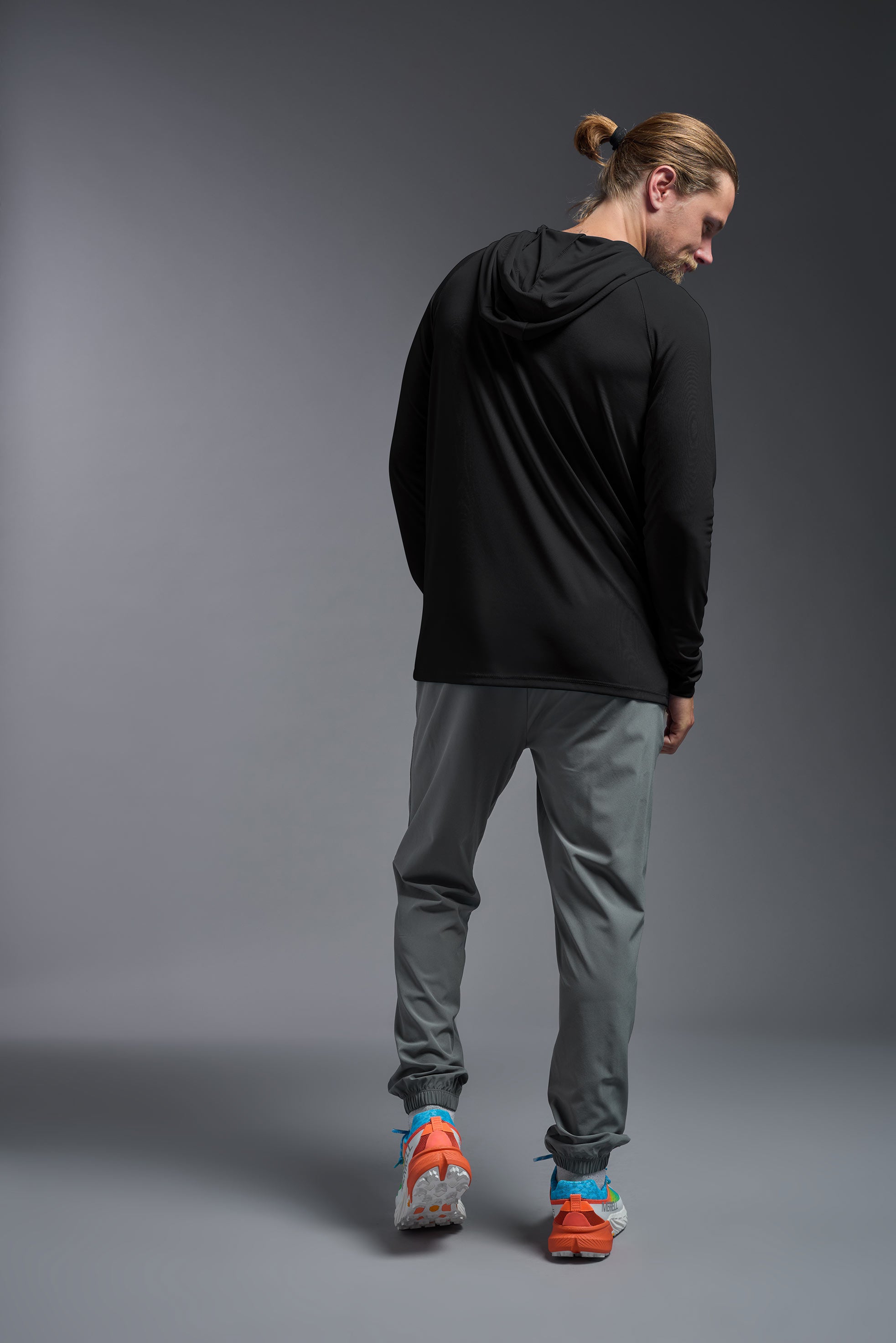 A male model wearing the men's DriMax Lightweight Hoodie in the color black, made out of 100% polyester, showing the relaxed fit from a back view. #black
