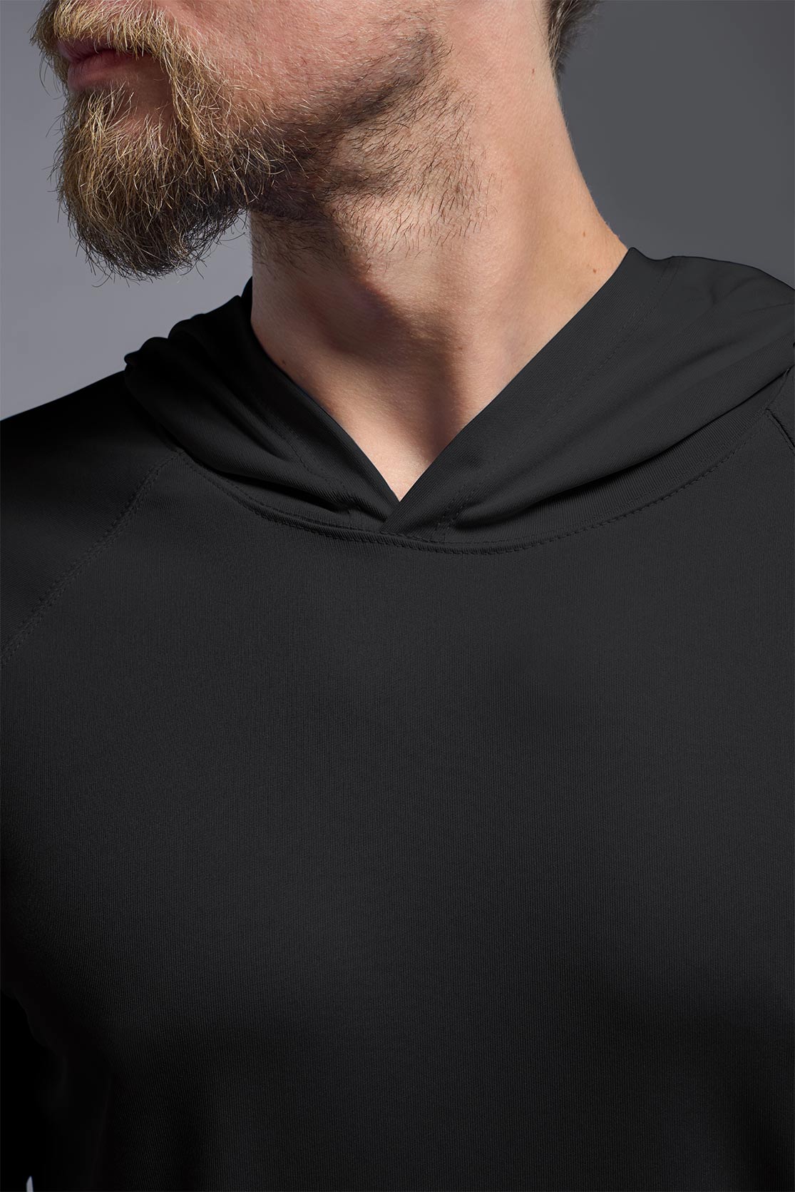 A male model wearing the men's DriMax Lightweight Hoodie in the color black, made out of 100% polyester, showing the relaxed fit from a close-up collar view. #black