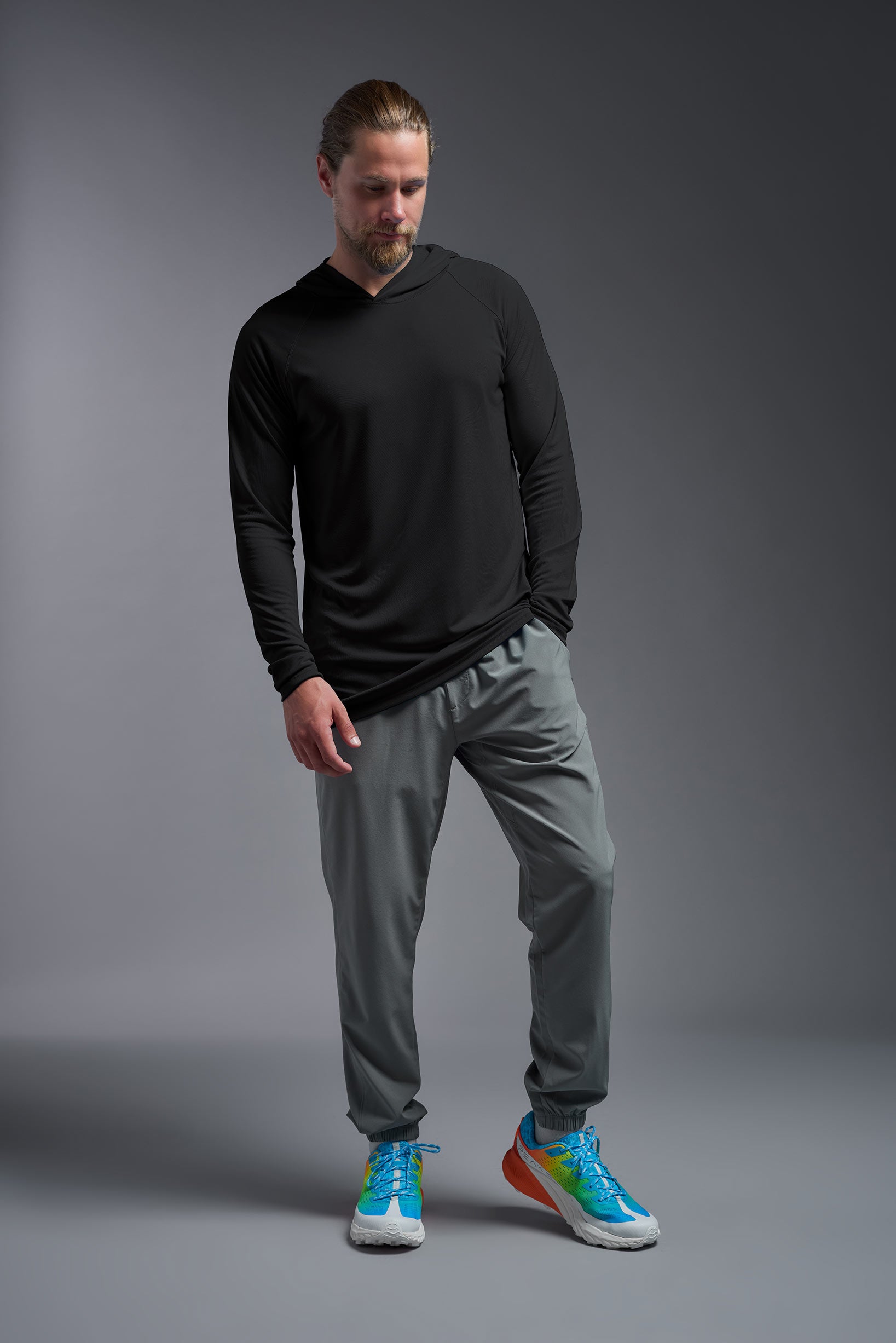 A male model wearing the men's DriMax Lightweight Hoodie in the color black, made out of 100% polyester, showing the relaxed fit from a front view. #black