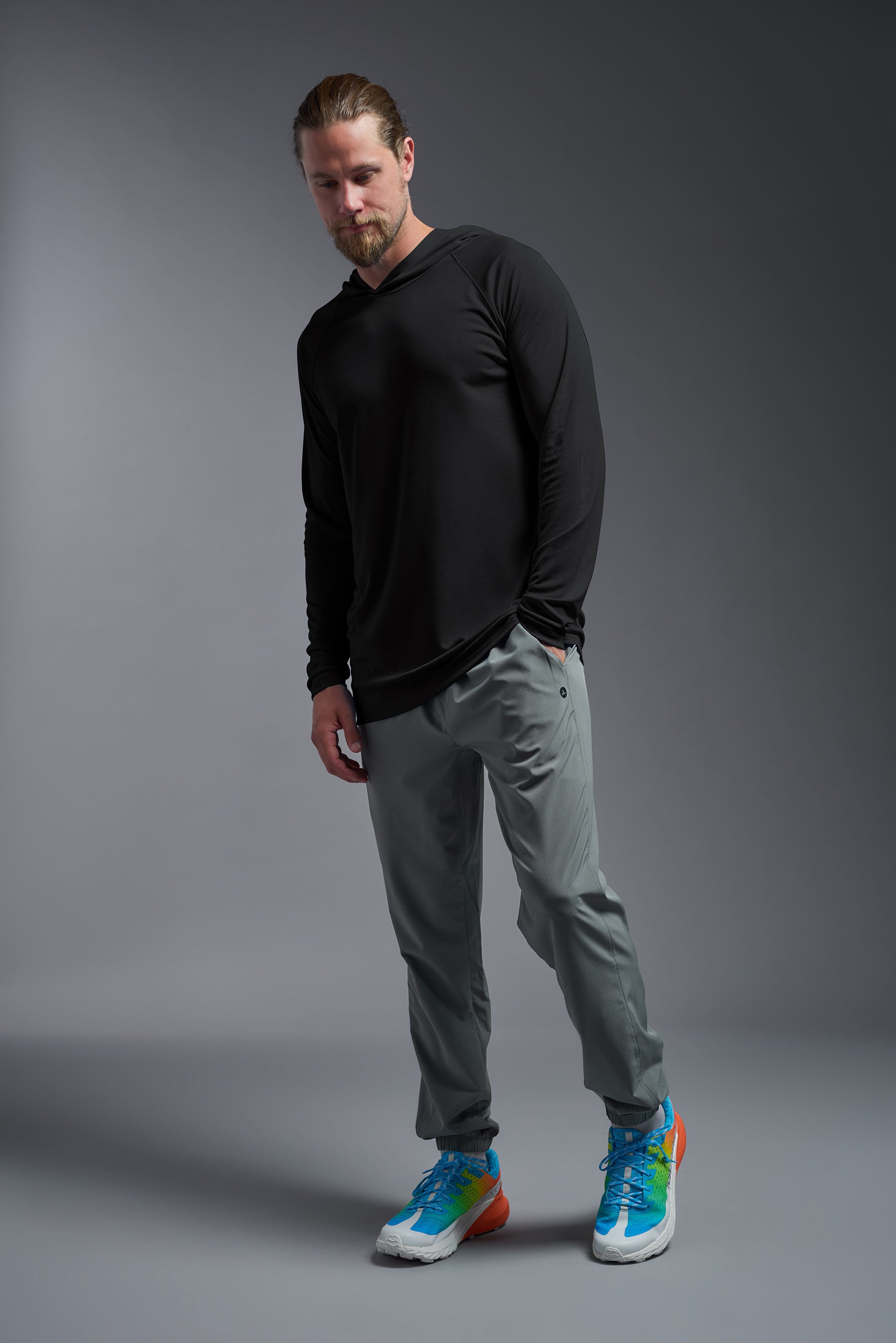 A male model wearing the men's DriMax Lightweight Hoodie in the color black, made out of 100% polyester, showing the relaxed fit from a side view. #black