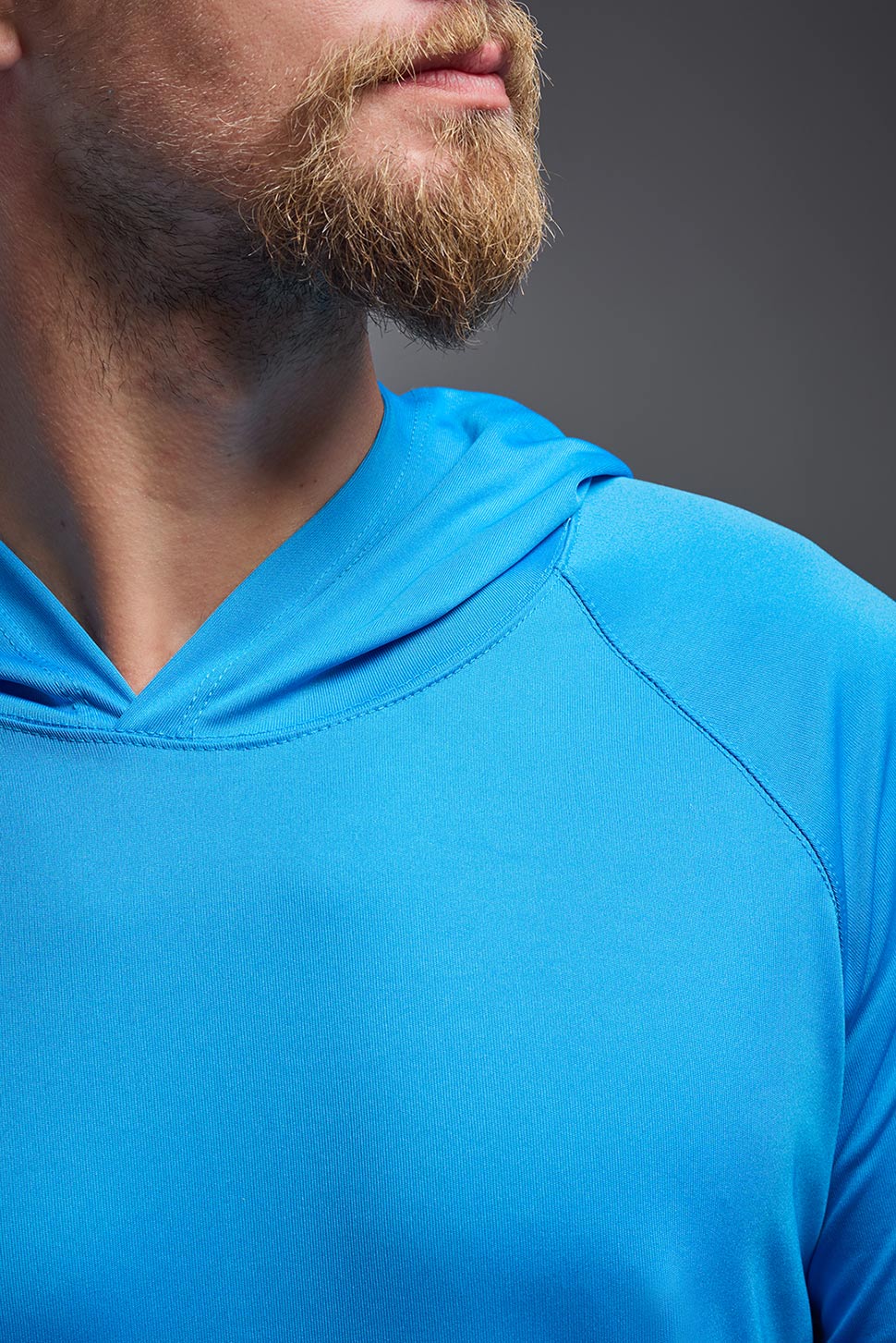 A male model wearing the men's DriMax Lightweight Hoodie in the color safety blue, made out of 100% polyester, showing the relaxed fit from a close-up collar view. #safety-blue