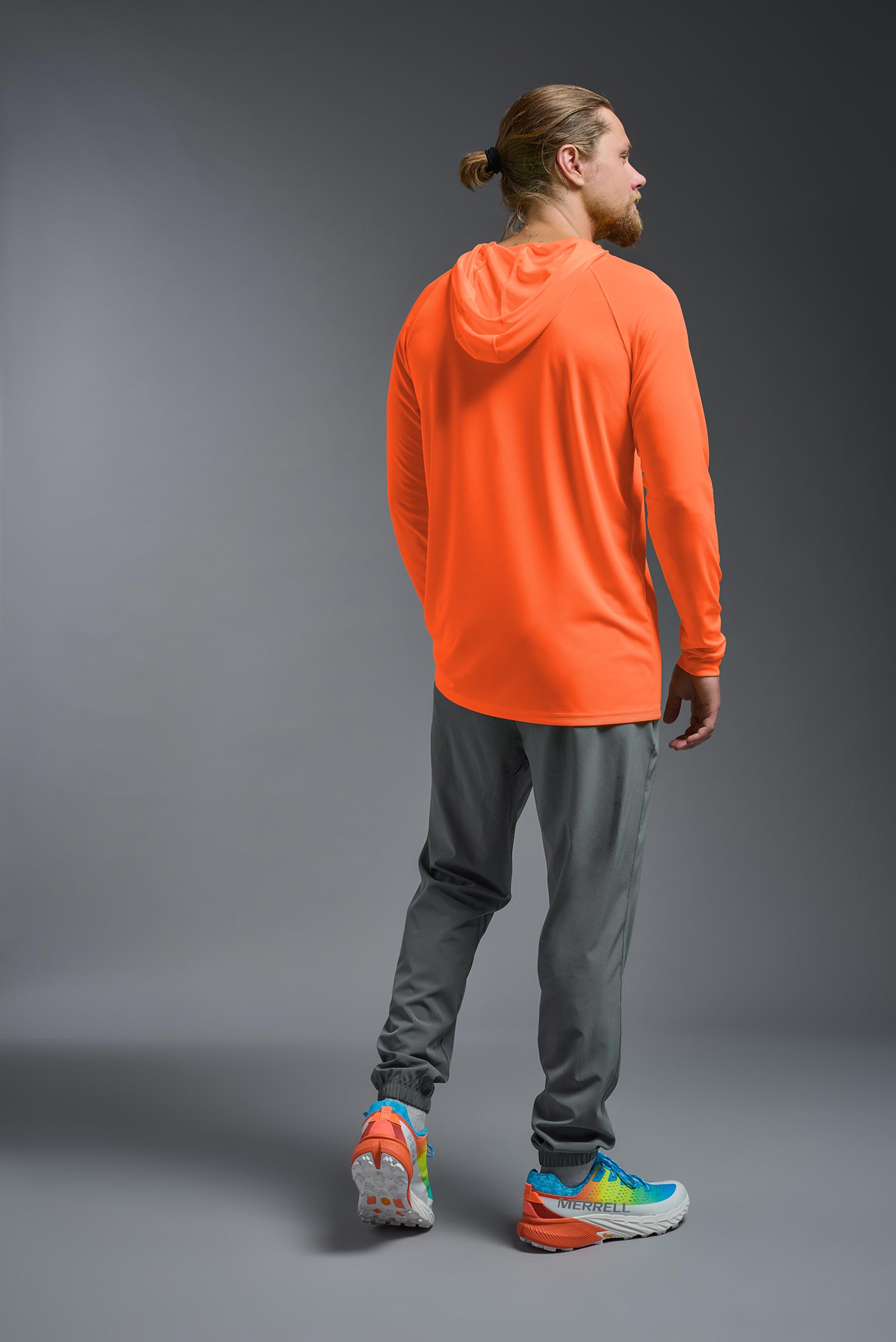 A male model wearing the men's DriMax Lightweight Hoodie in safety orange, made out of 100% double-knit interlock polyester, showing the relaxed fit from a back view. #safety-orange