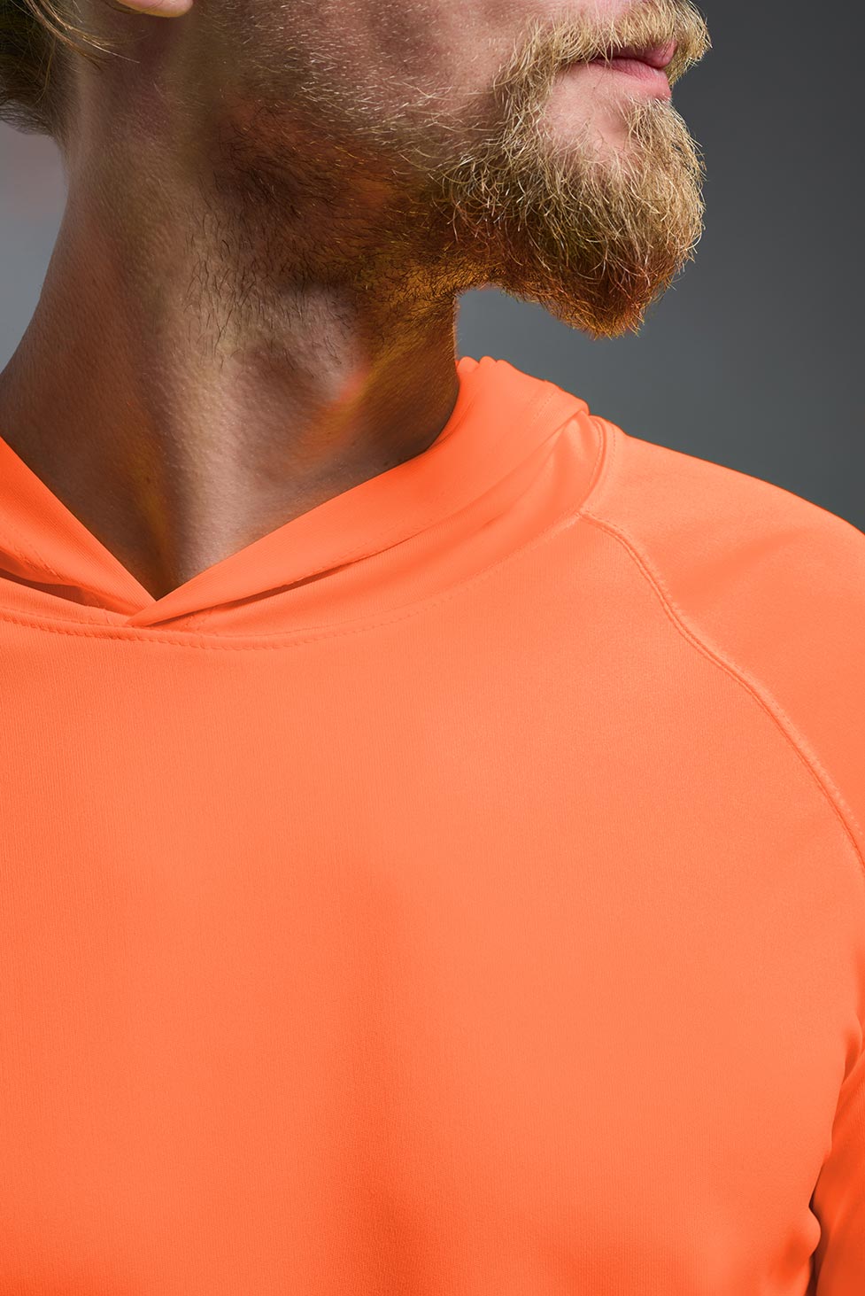 A male model wearing the men's DriMax Lightweight Hoodie in safety orange, made out of 100% double-knit interlock polyester, showing the relaxed fit from a front close-up collar view. #safety-orange