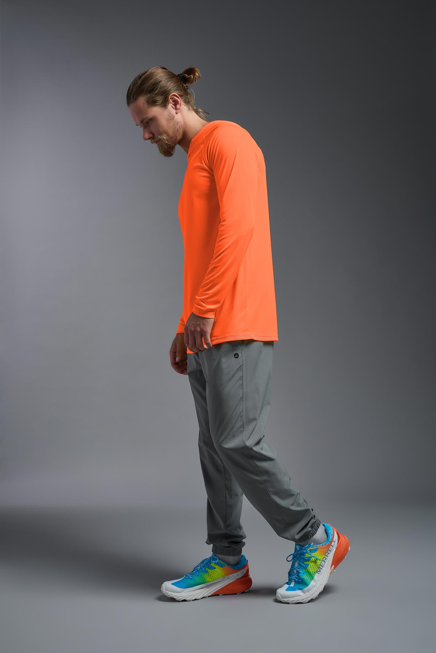 A male model wearing the men's DriMax Lightweight Hoodie in safety orange, made out of 100% double-knit interlock polyester, showing the relaxed fit from a side view. #safety-orange
