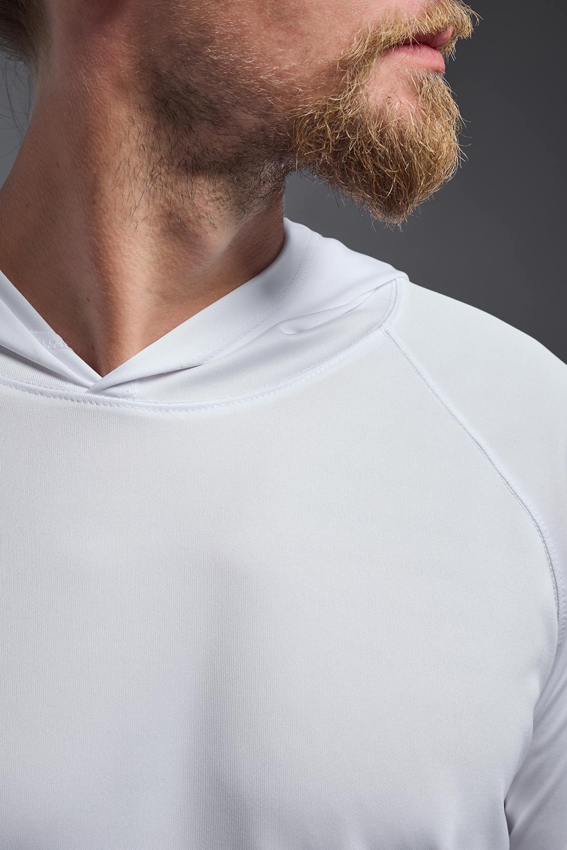 A male model wearing the men's DriMax Lightweight Hoodie in the color white, made out of 100% polyester, showing the relaxed fit from a close-up collar view. #white