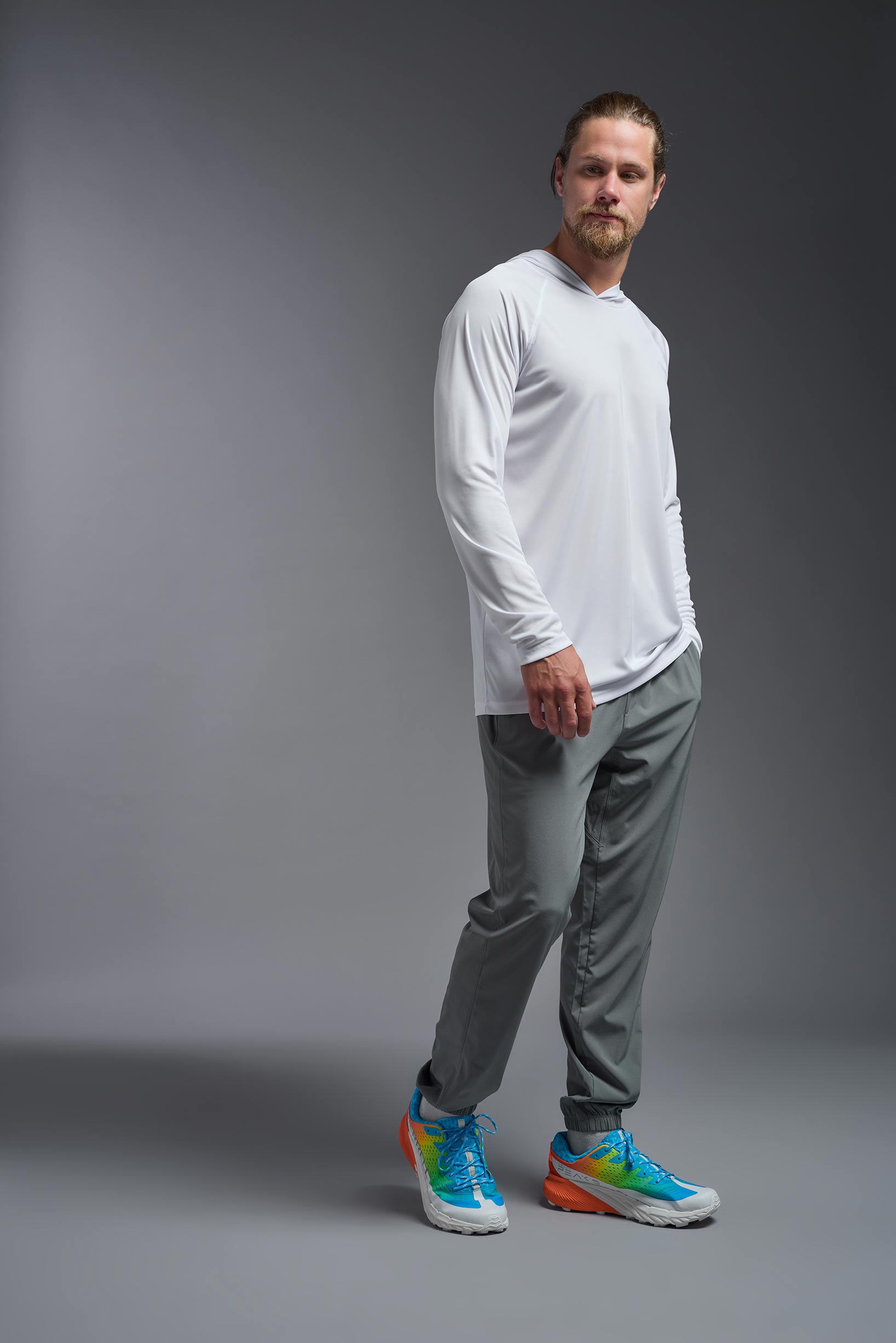 A male model wearing the men's DriMax Lightweight Hoodie in the color white, made out of 100% polyester, showing the relaxed fit from a side view. #white