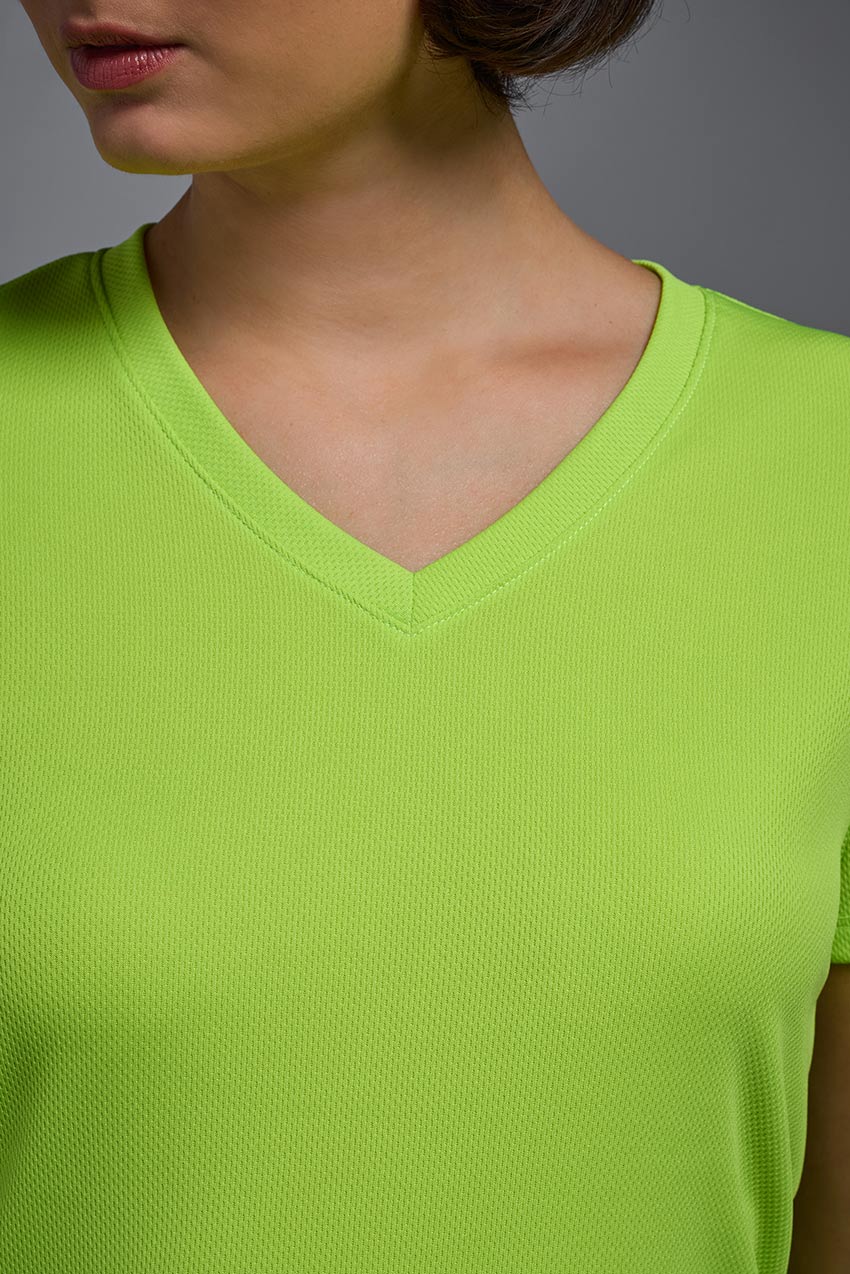 A female model wearing the women's Oxymesh V-neck Tech Tee Imported Version in the color key lime, made out of 100% polyester, showing the relaxed fit from a close-up collar view. This shirt is breathable, quick-drying, moisture-wicking, and Imported for a better price on bulk apparel. #key-lime