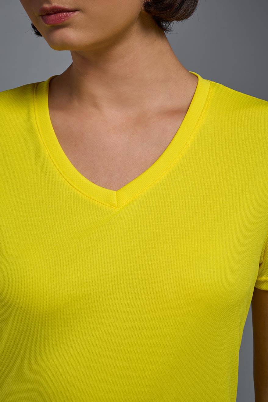 A female model wearing the women's Oxymesh V-neck Tech Tee in the color bright yellow, made out of 100% polyester, showing the relaxed fit from a close-up collar view. This shirt is breathable, wicks away moisture, quick-dries, and is made in the USA. #bright-yellow