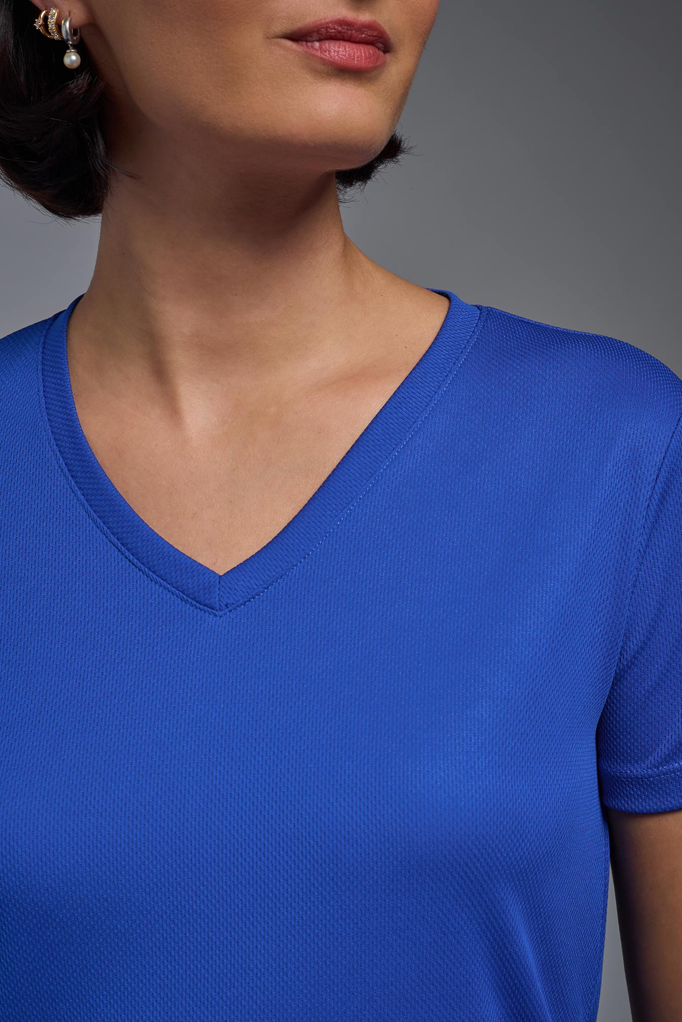 A female model wearing the women's Oxymesh V-neck Tech Tee in the color royal blue, made out of 100% polyester, showing the relaxed fit from a close-up collar view. This shirt is breathable, wicks away moisture, quick-dries, and is made in the USA. #royal-blue
