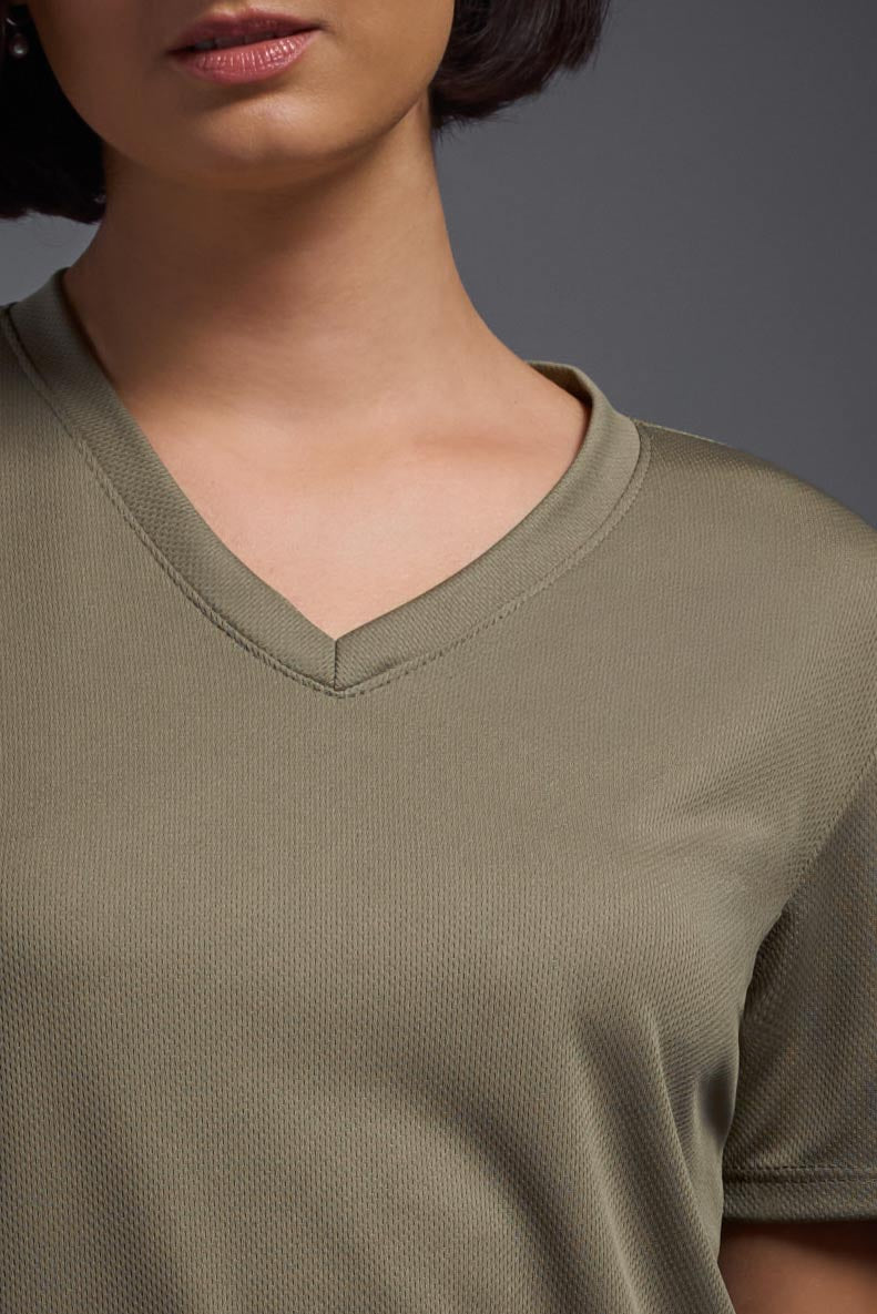 A female model wearing the women's Oxymesh V-neck Tech Tee in the color tan, made out of 100% polyester, showing the relaxed fit from a close-up collar view. This shirt is breathable, wicks away moisture, quick-dries, and is made in the USA. #tan