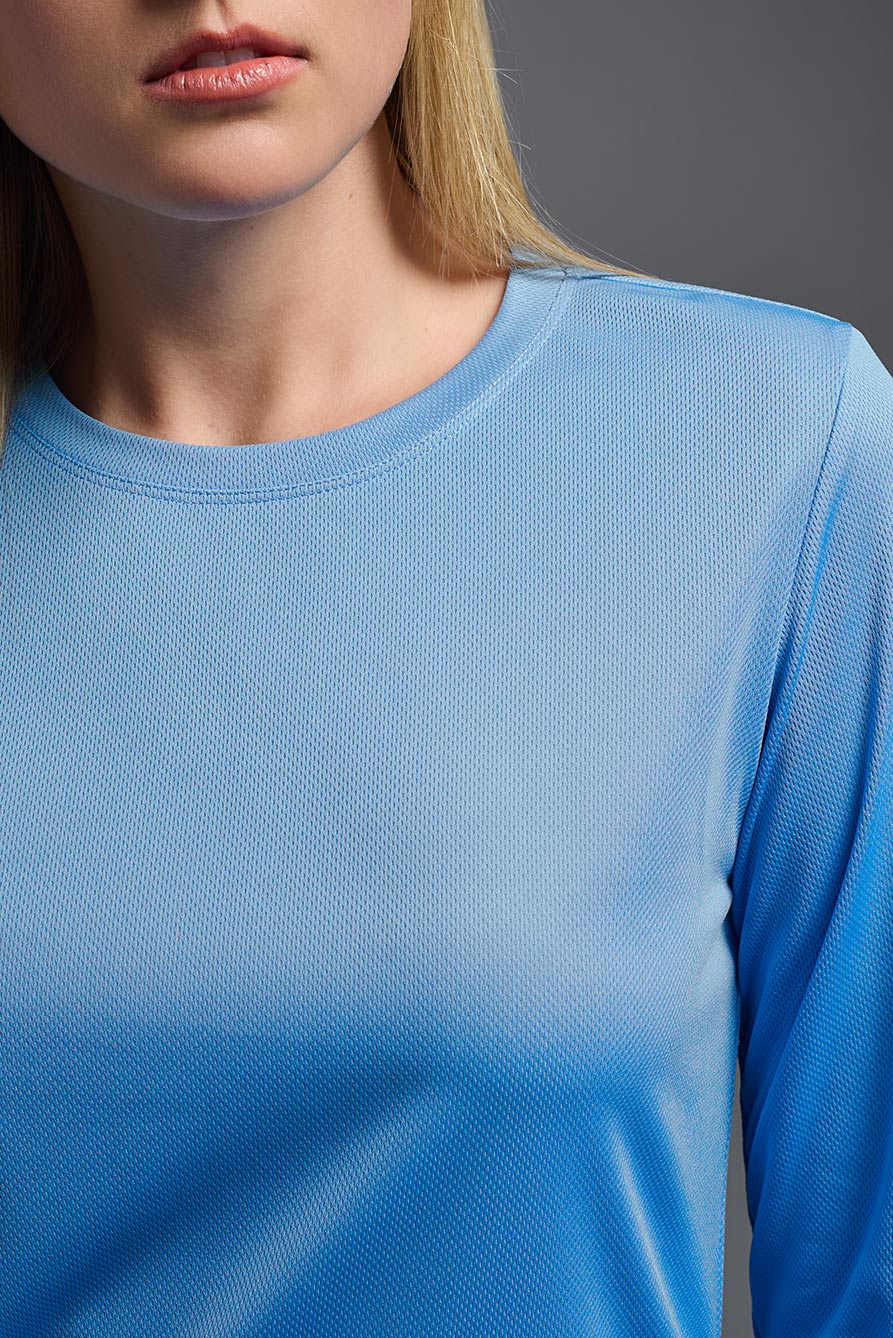 A female model wearing the women's Oxymesh Long Sleeve Tech Tee Imported Version in the color carolina blue, made out of 100% polyester, showing the relaxed fit from a front close-up collar view. This shirt is breathable, quick-drying, moisture-wicking, and Imported for a better price on bulk apparel. #carolina-blue