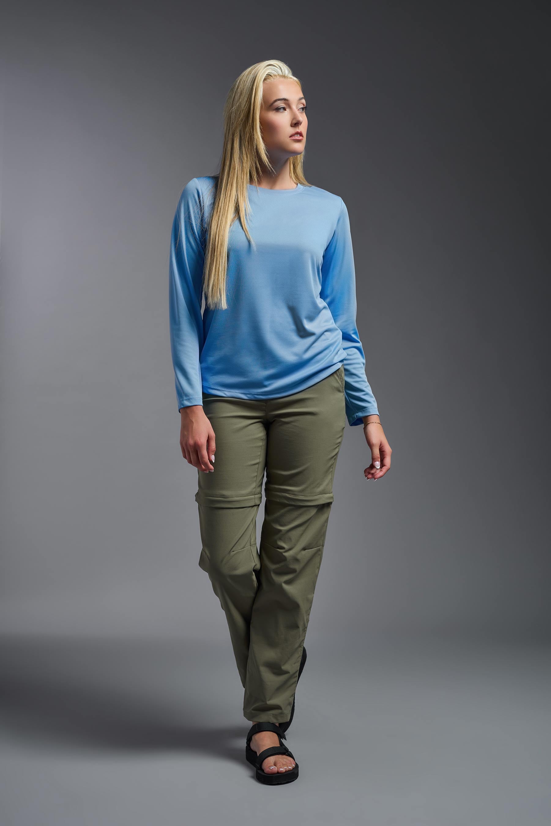 A female model wearing the women's Oxymesh Long Sleeve Tech Tee Imported Version in the color carolina blue, made out of 100% polyester, showing the relaxed fit from a front view. This shirt is breathable, quick-drying, moisture-wicking, and Imported for a better price on bulk apparel. #carolina-blue