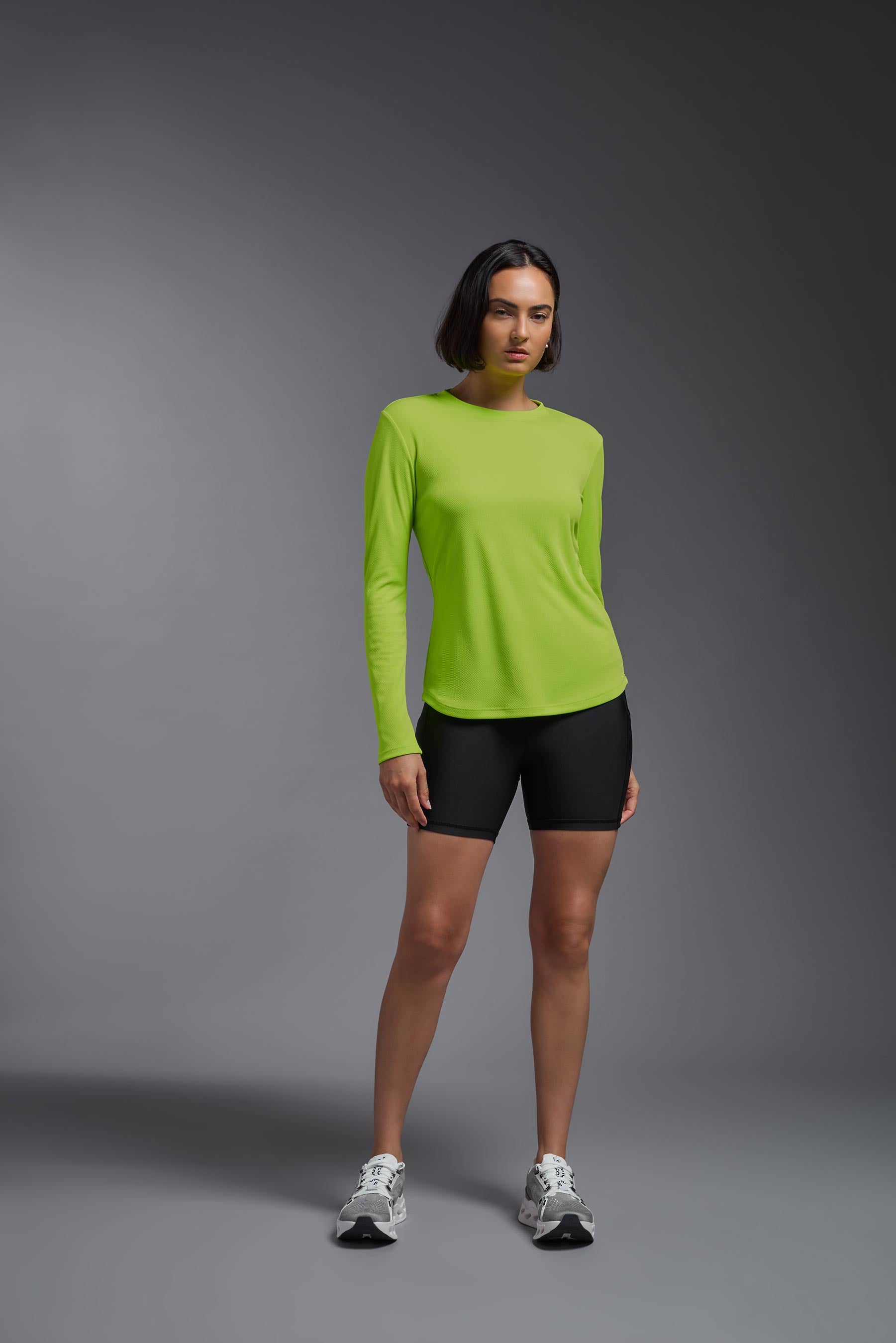 A female model wearing the women's Oxymesh Long Sleeve Tech Tee Imported Version in the color key lime, made out of 100% polyester, showing the relaxed fit from a front view. This shirt is breathable, quick-drying, moisture-wicking, and Imported for a better price on bulk apparel. #key-lime