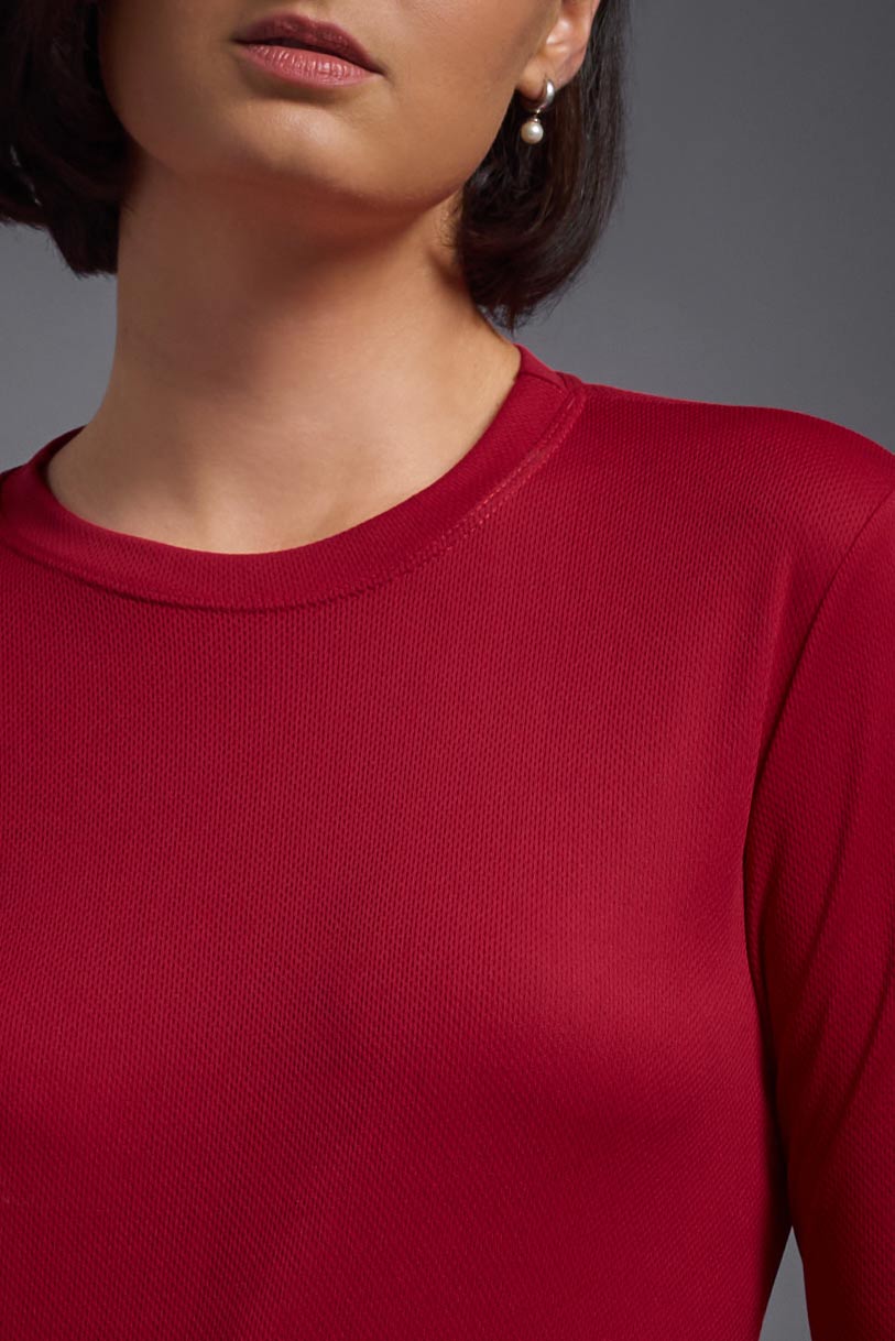 A female model wearing the women's Oxymesh Long Sleeve Tech Tee Imported Version in the color true red, made out of 100% polyester, showing the relaxed fit from a front close-up collar view. This shirt is breathable, quick-drying, moisture-wicking, and Imported for a better price on bulk apparel. #true-red