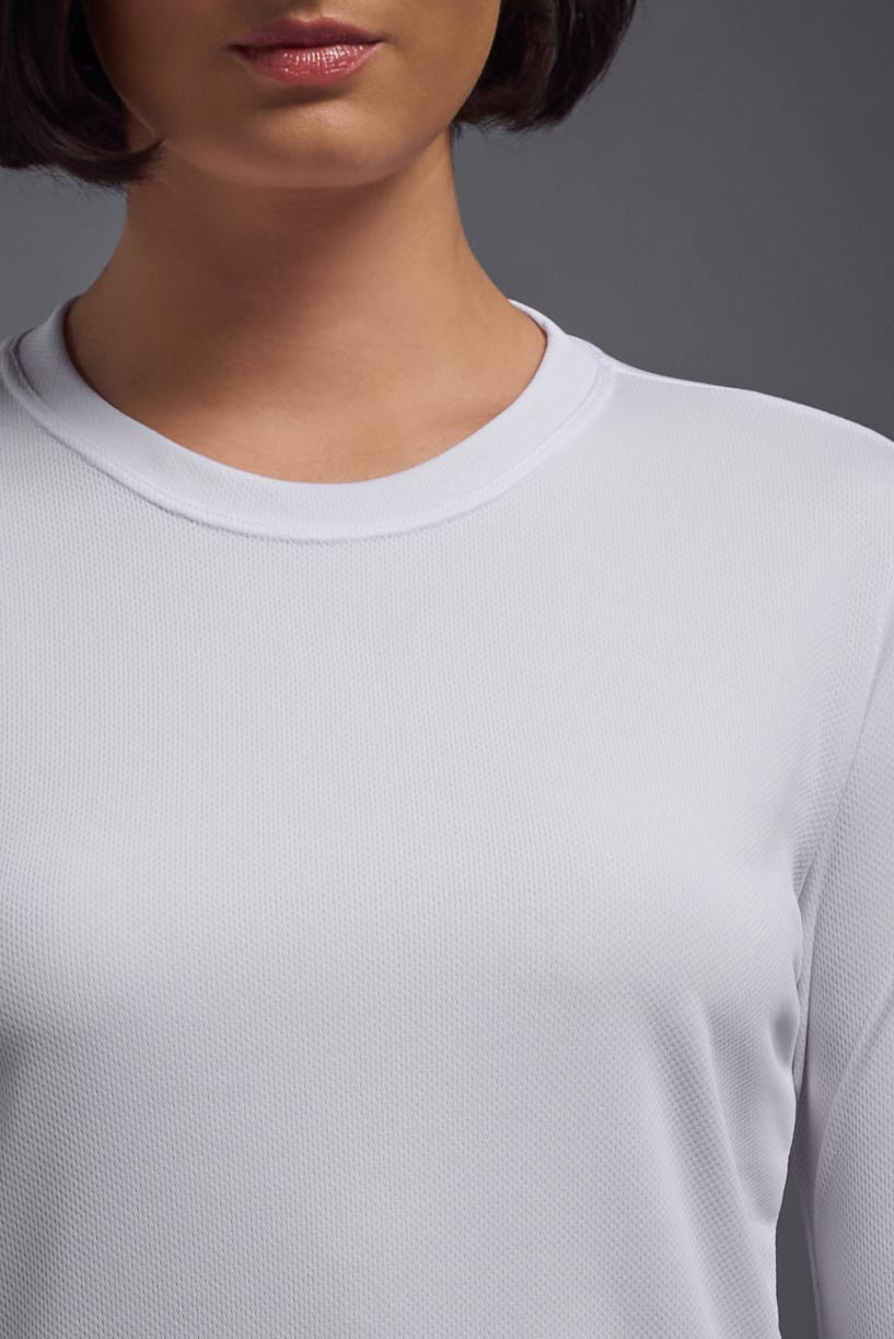 A female model wearing the women's Oxymesh Long Sleeve Tech Tee Imported Version in the color white, made out of 100% polyester, showing the relaxed fit from a front close-up collar view. This shirt is breathable, quick-drying, moisture-wicking, and Imported for a better price on bulk apparel. #white