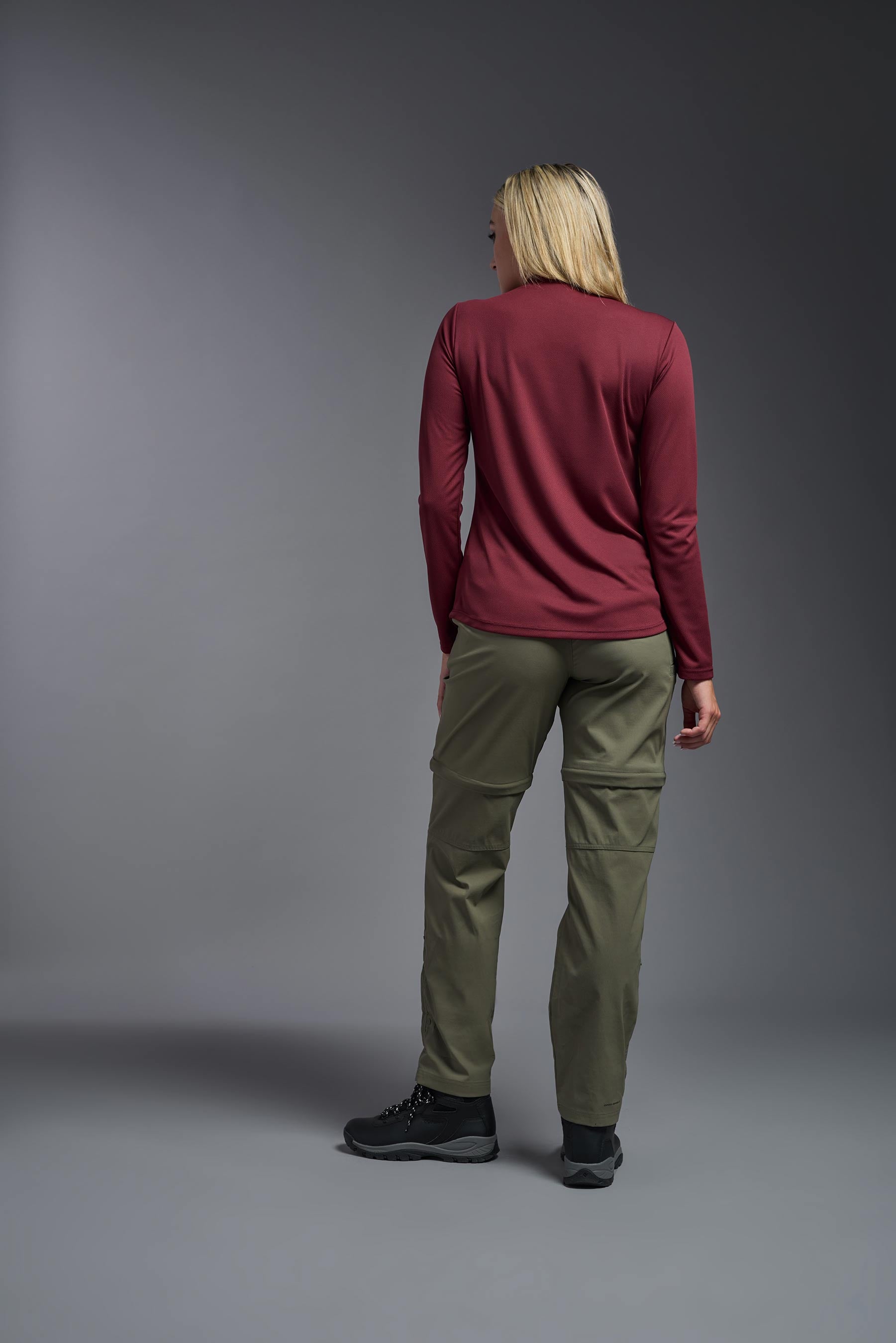 A female model wearing the women's Oxymesh Long Sleeve Tech Tee in the color cardinal, made out of 100% polyester, showing the relaxed fit from a back view. This shirt is breathable, quick-drying, moisture-wicking, and made in the USA. #cardinal-red